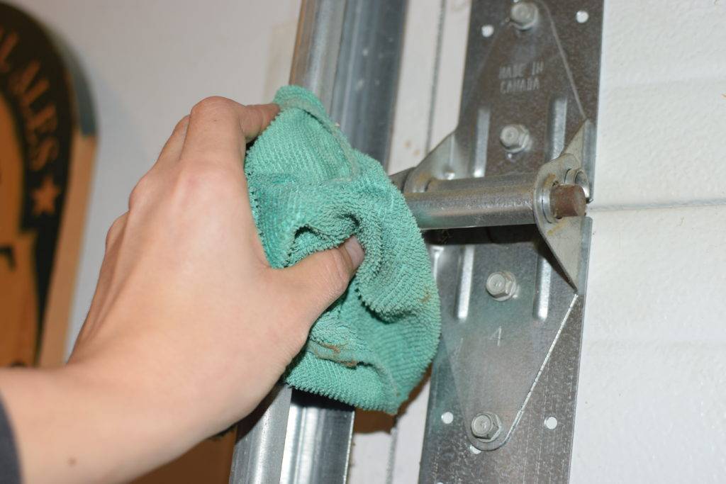 How to Fix a Squeaky Garage Door - HanD HolDing Rug To Dust Hinges.jpg 44687 1024x683