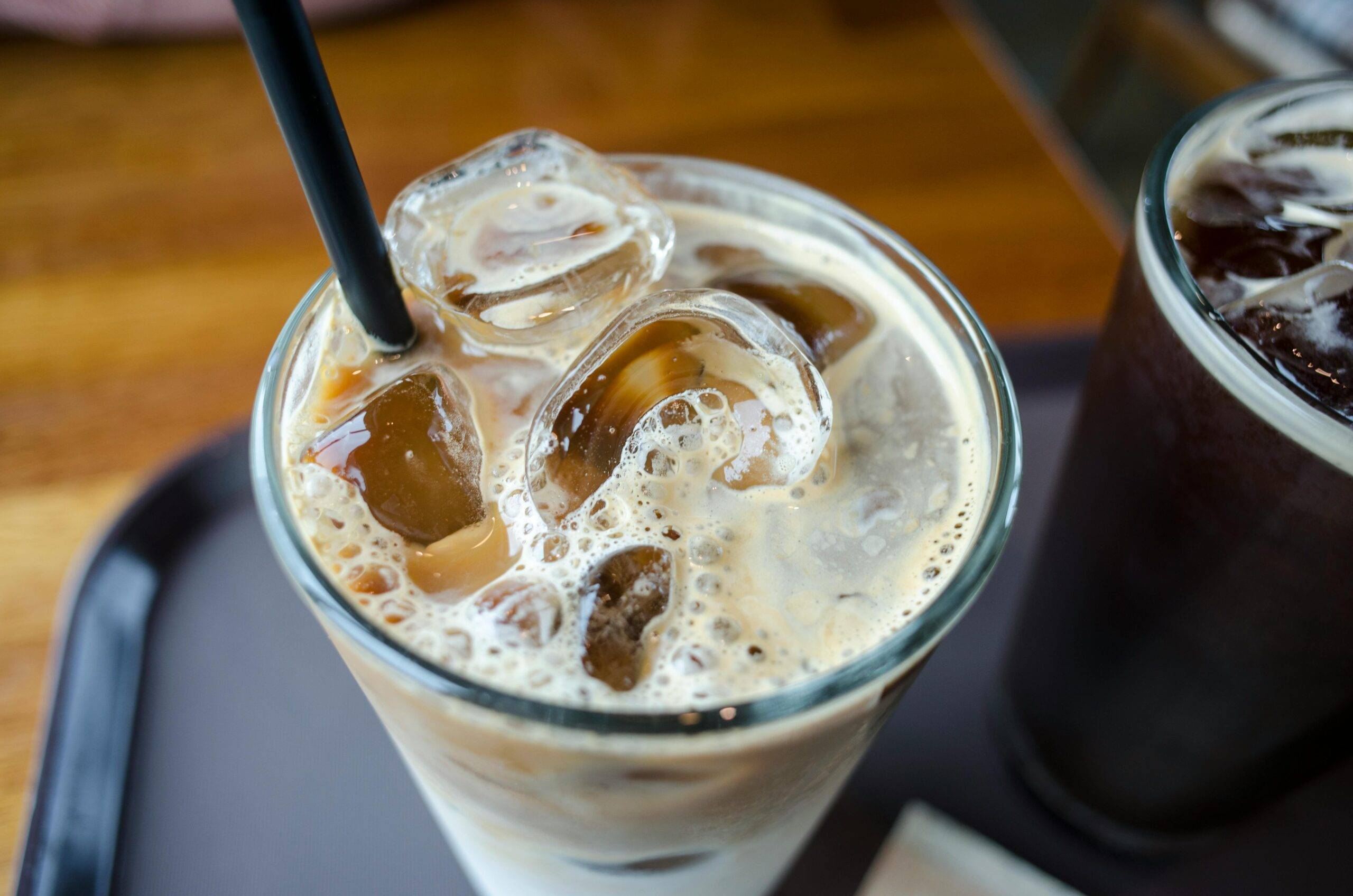 frothy milk cold brew in glass with straw and ice