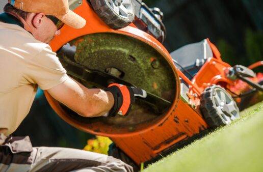 man checking blades on lawn mower outdoors