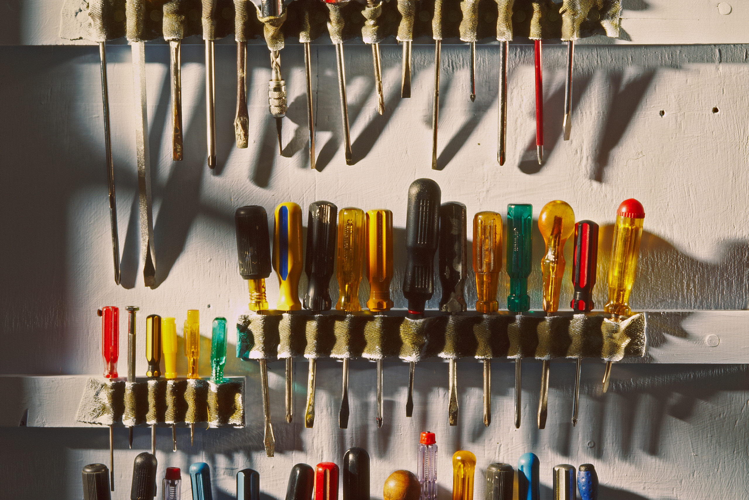 An assortment of screwdrivers mounted onto a wall.