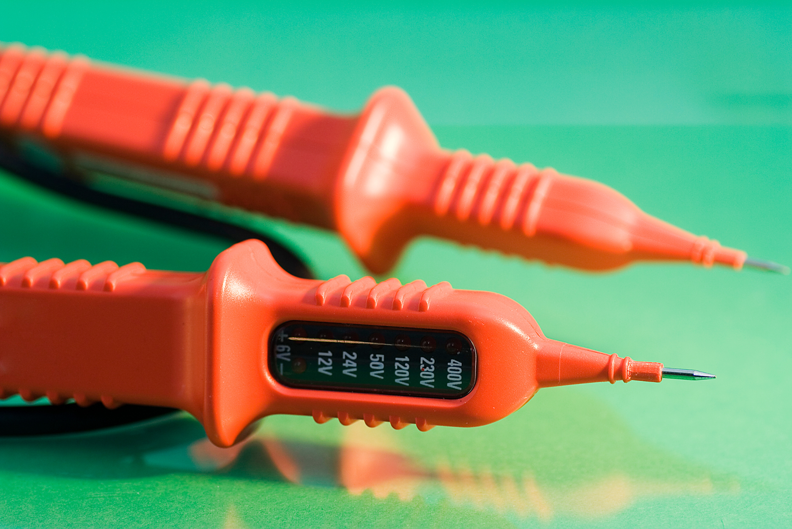 A red voltage tester on a green background.