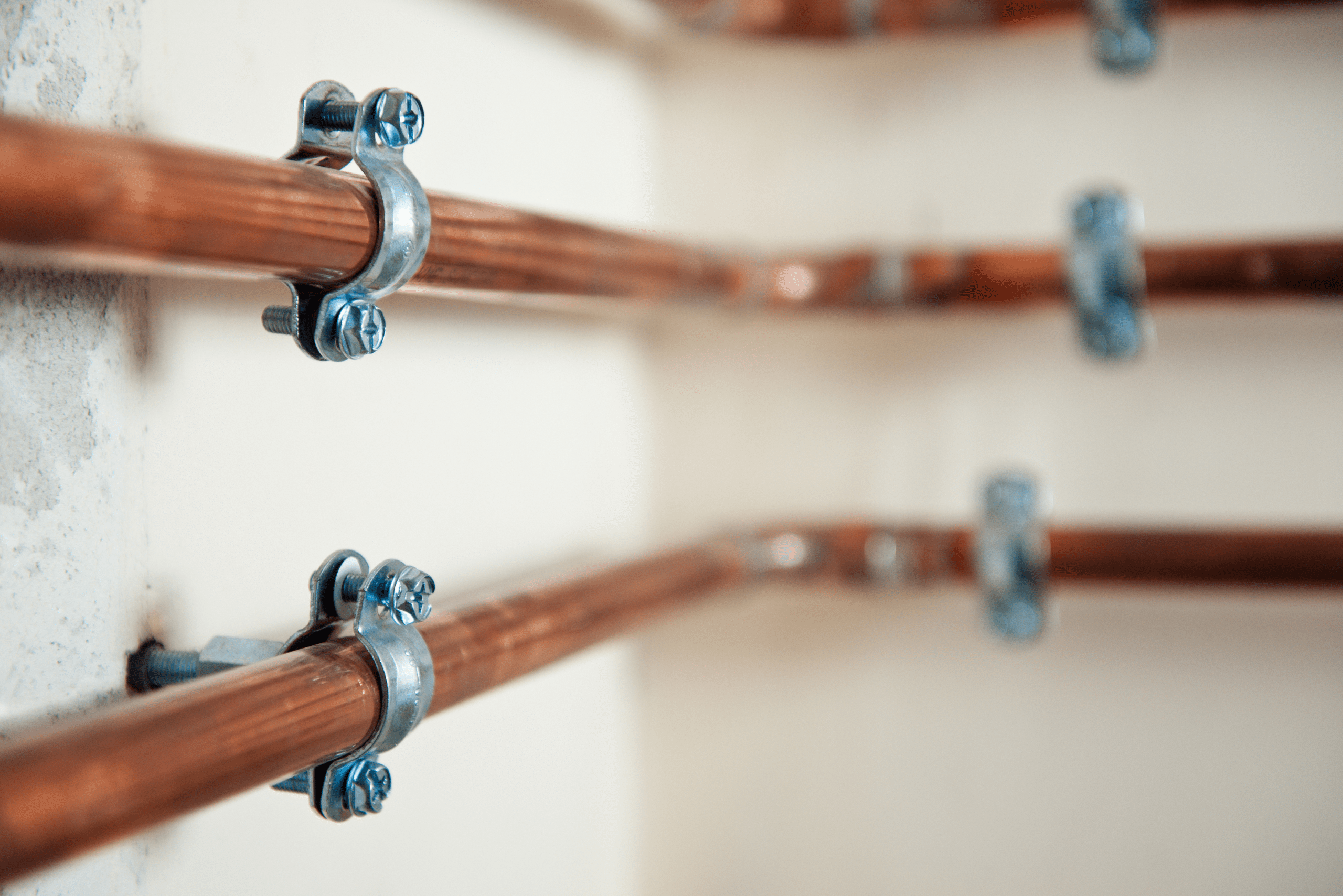 Multiple copper pipes mounted onto a wall.