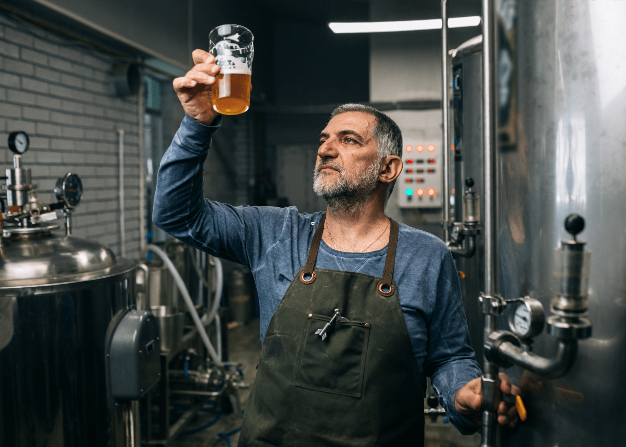 man making beer holding up glass of beer
