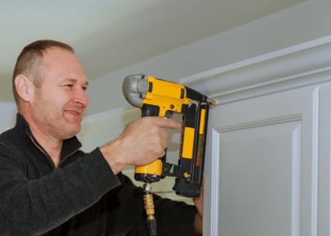 man using a brad nailer to nail in trim work