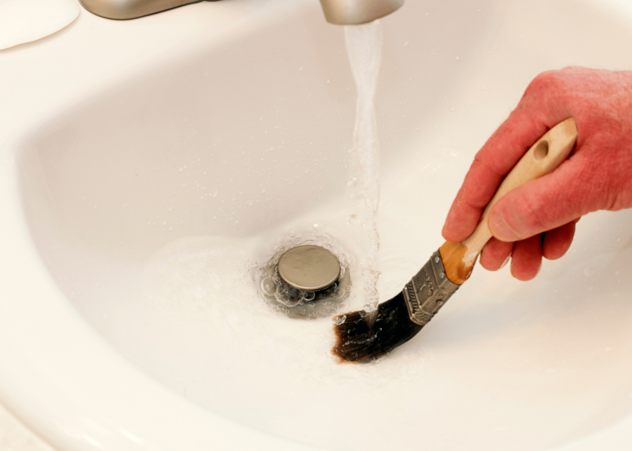 cleaning paint brush in sink