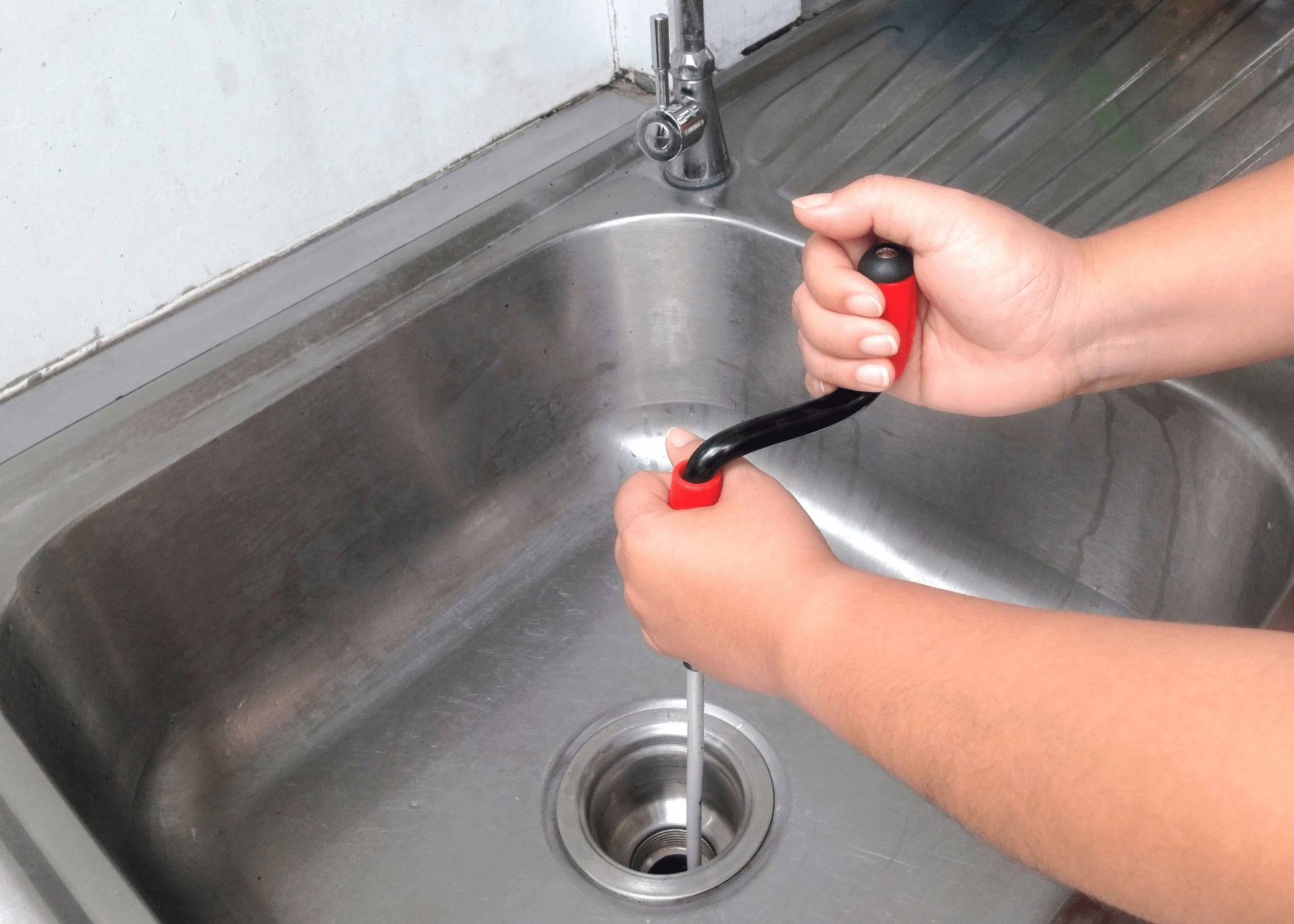 clogged drain hands using snake to unclog