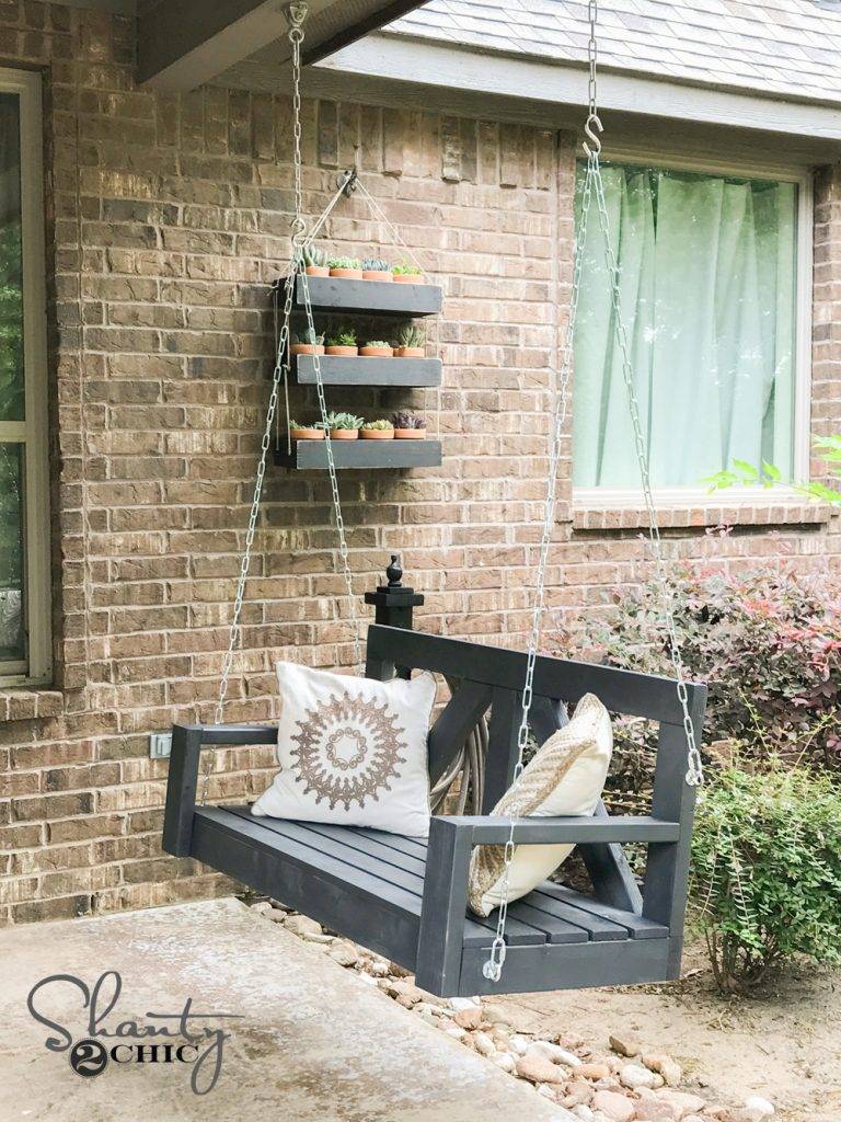 A grey patio swing with throw pillows.