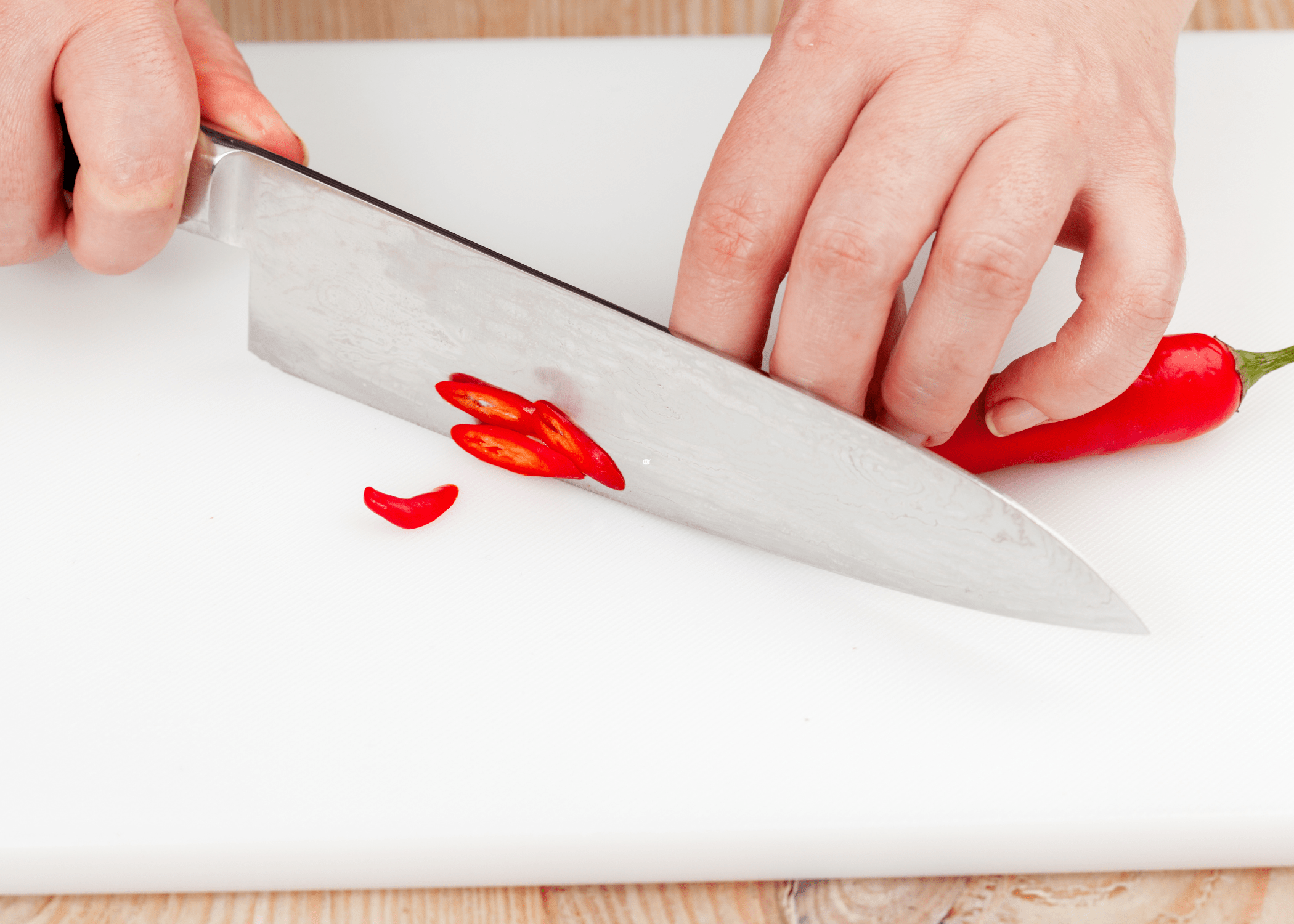 cutting red chili peppers on white cutting board