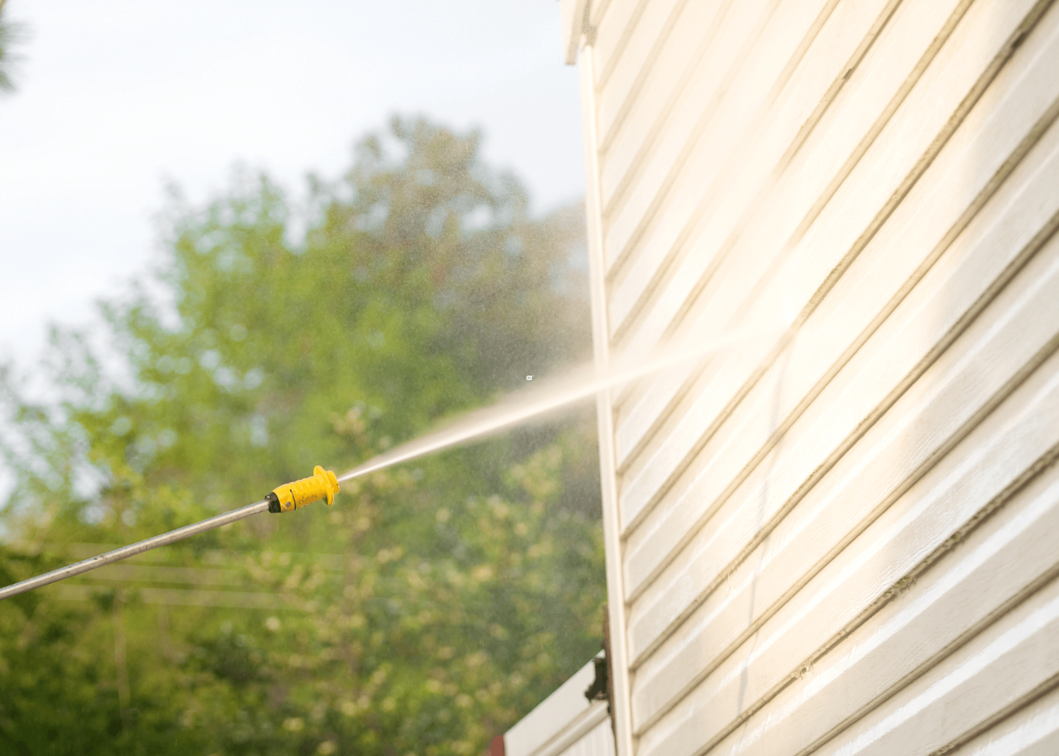 spraying siding with pressure washer