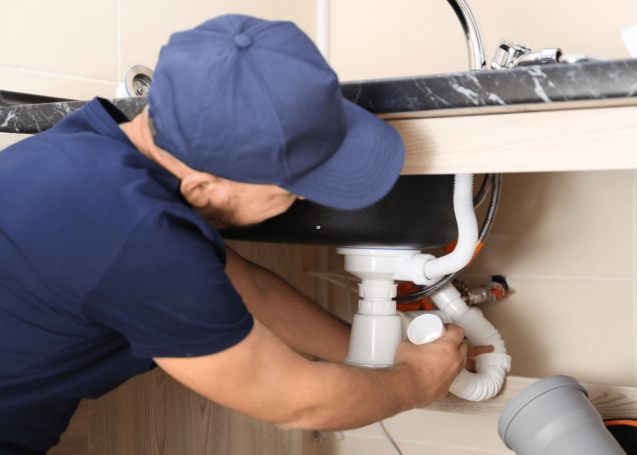man repairing pipe under sink