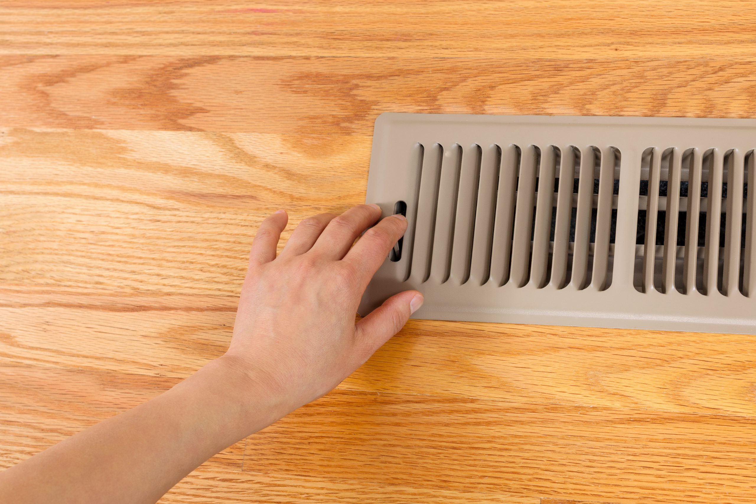 A hand reaching to close home vents.