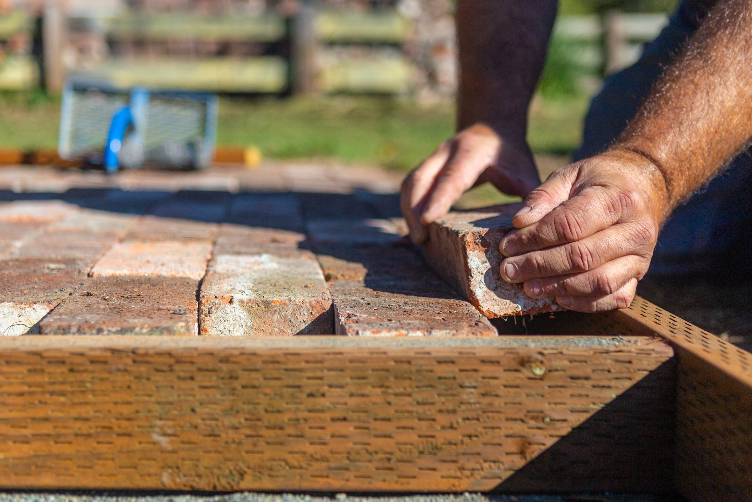 Closeup of someone laying down bricks to build fit pit.