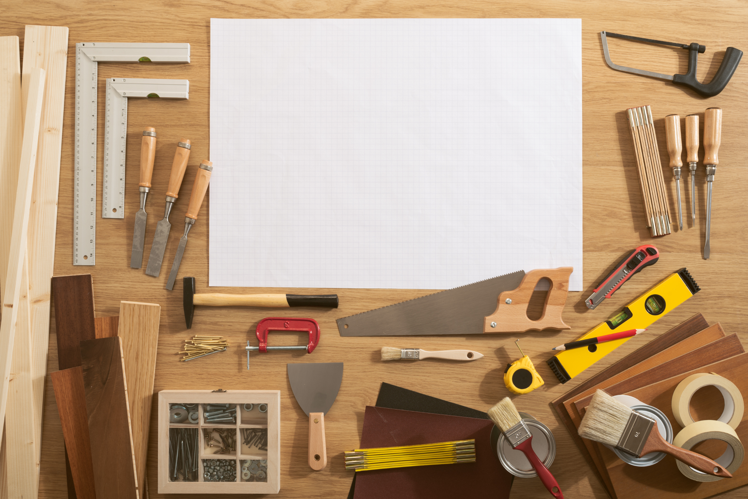 A bunch of different tools and empty white paper on table.