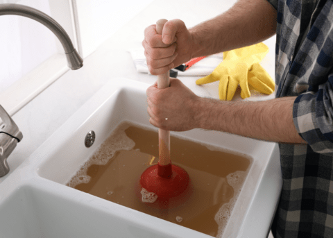 man plunging a clogged sink