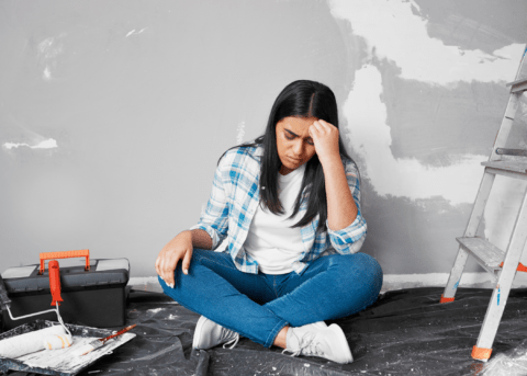 woman sitting in middle of renovation looking regretful and frustrated