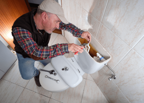 man fixing a running toilet