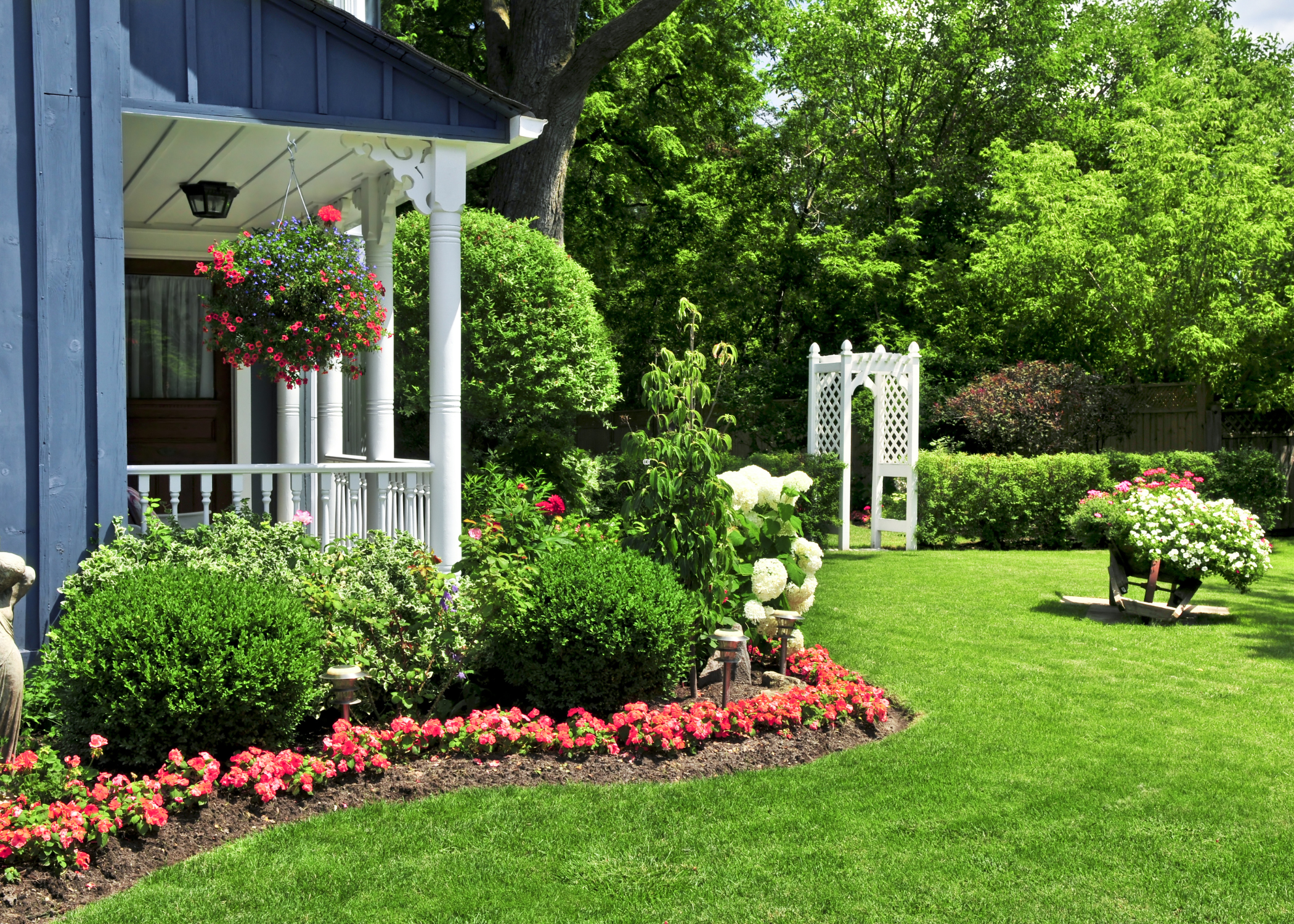front yard landscape with white porch and garden arch