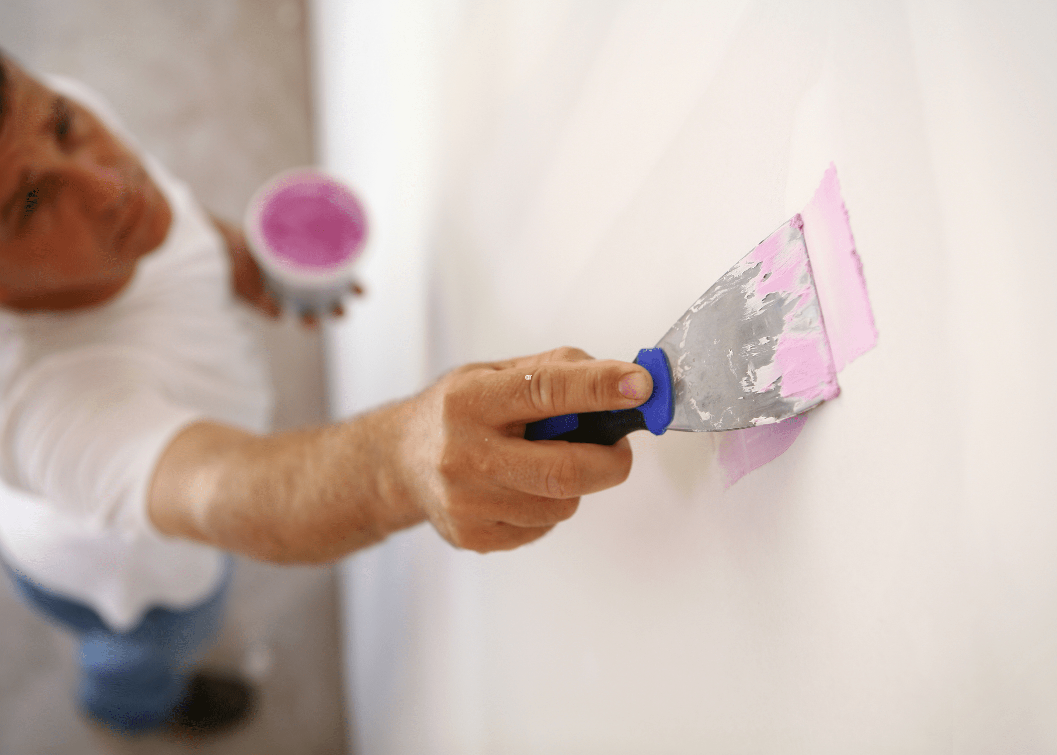 putty knife applying putty to wall