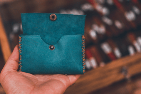 A hand holding a leather wallet.