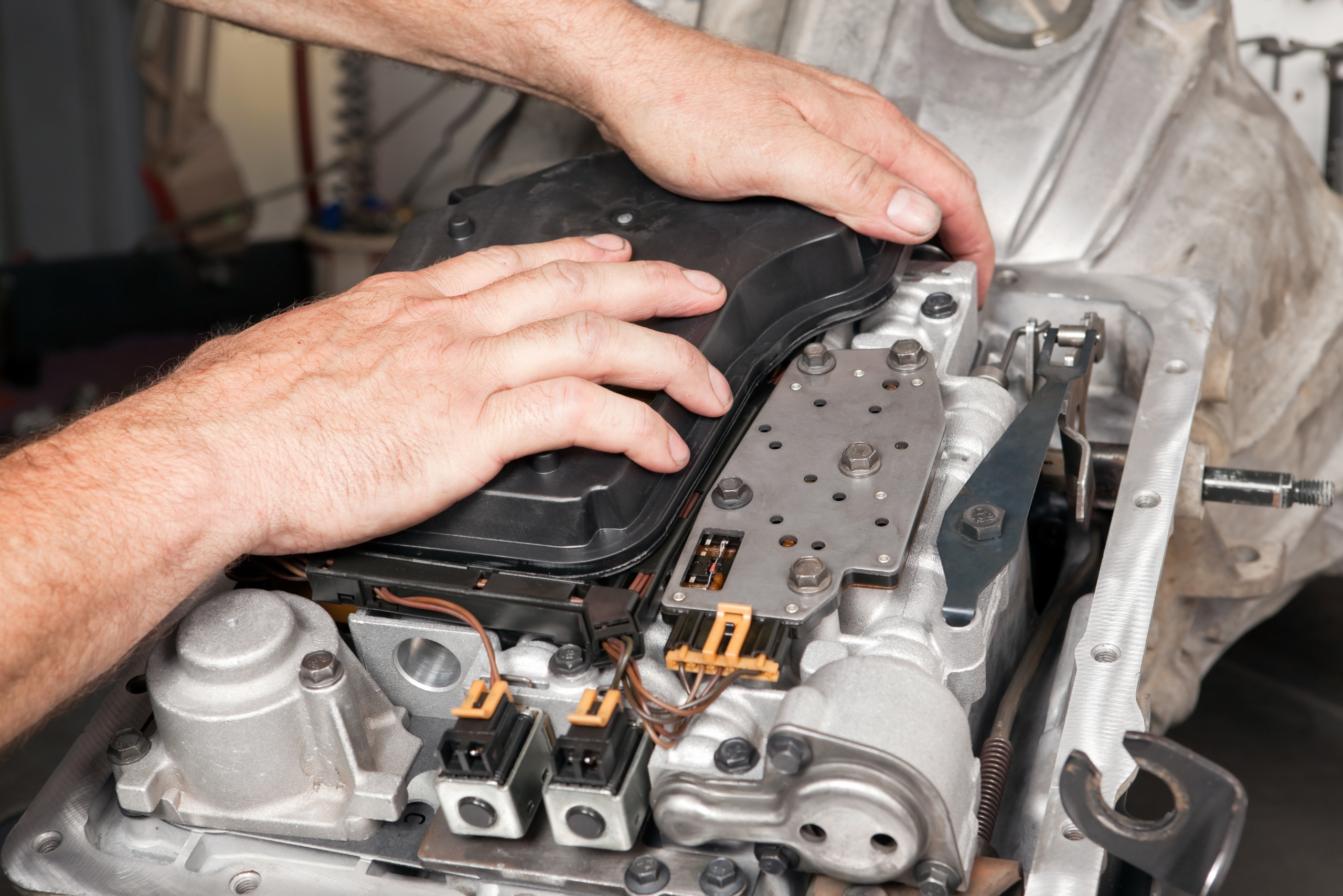 A person installing transmission filter on upside down transmission.