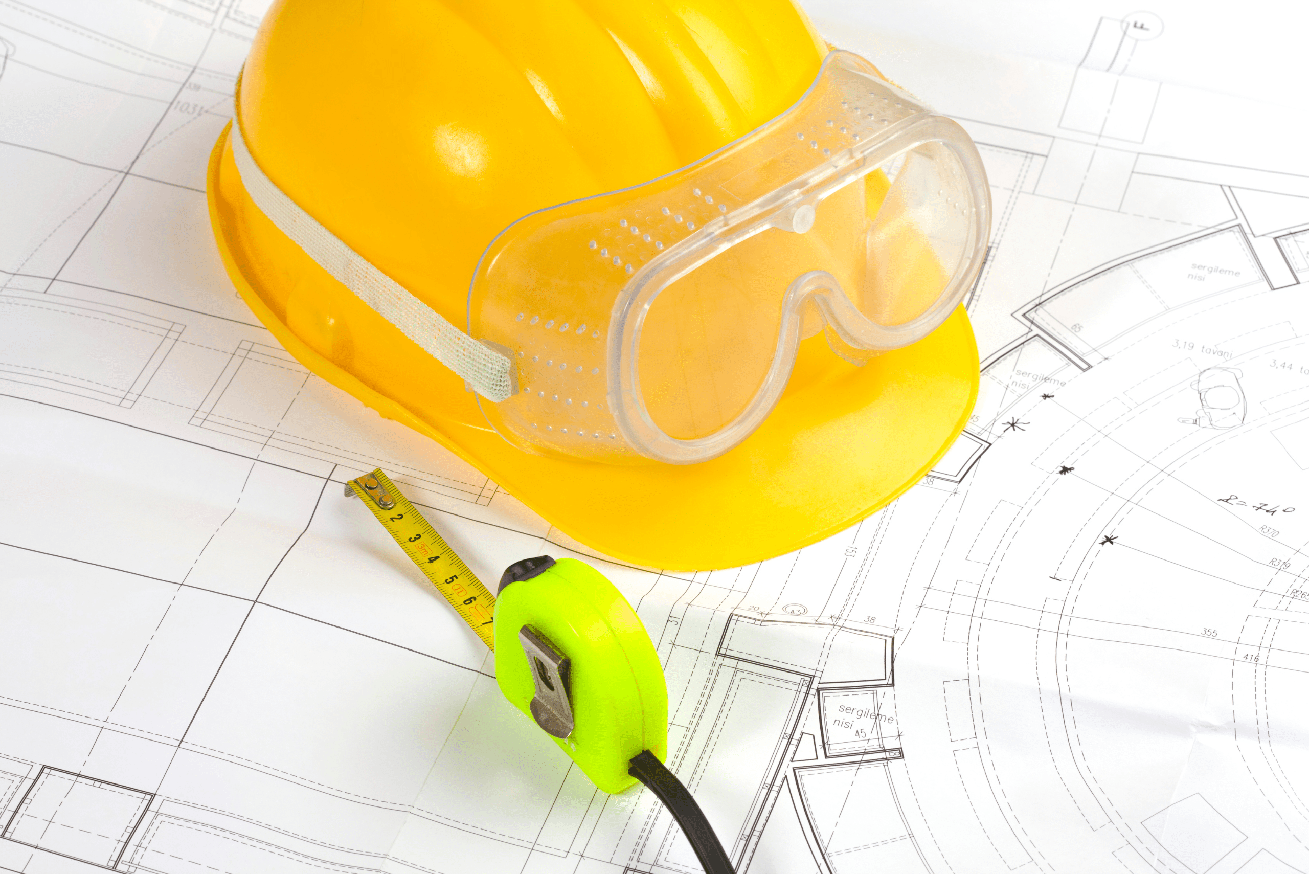 Measuring tape and hard hat on top of building plans.