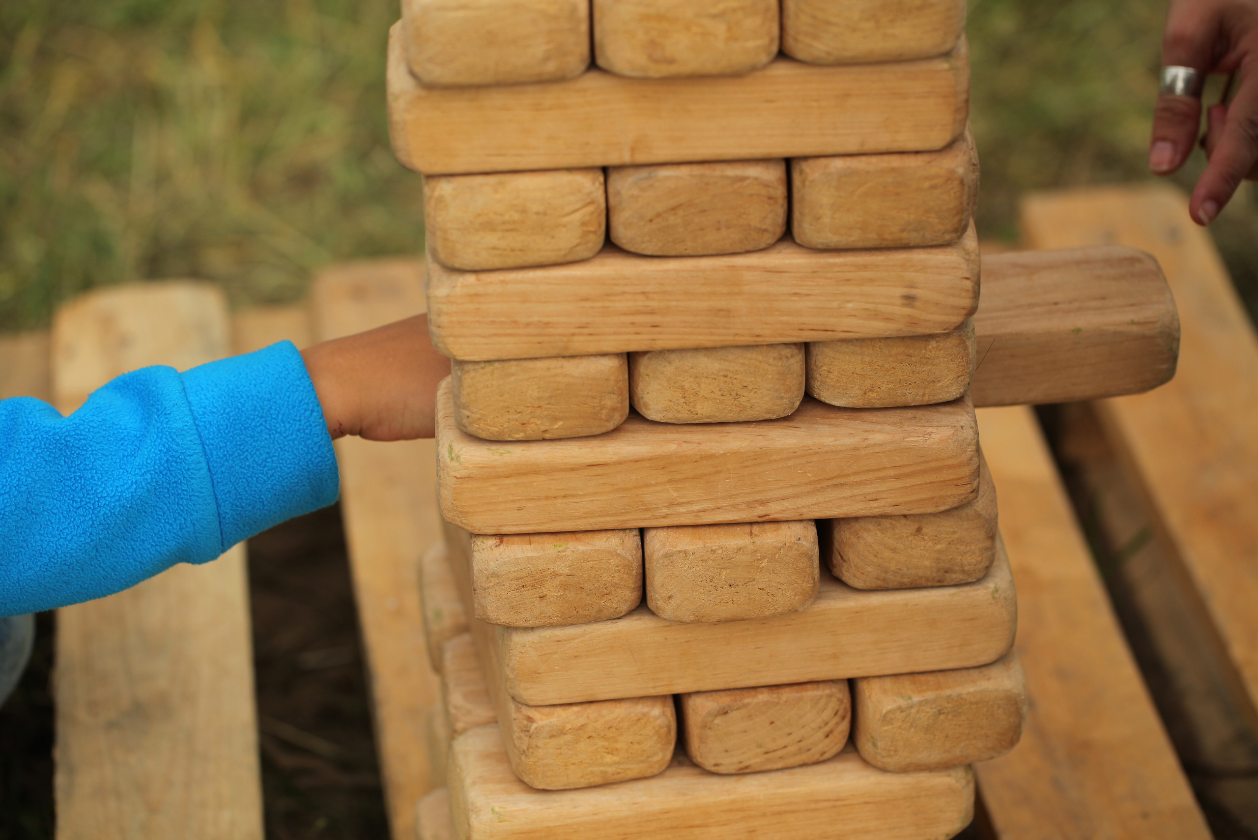 A boy pulling a piece from a giant Jenga game.