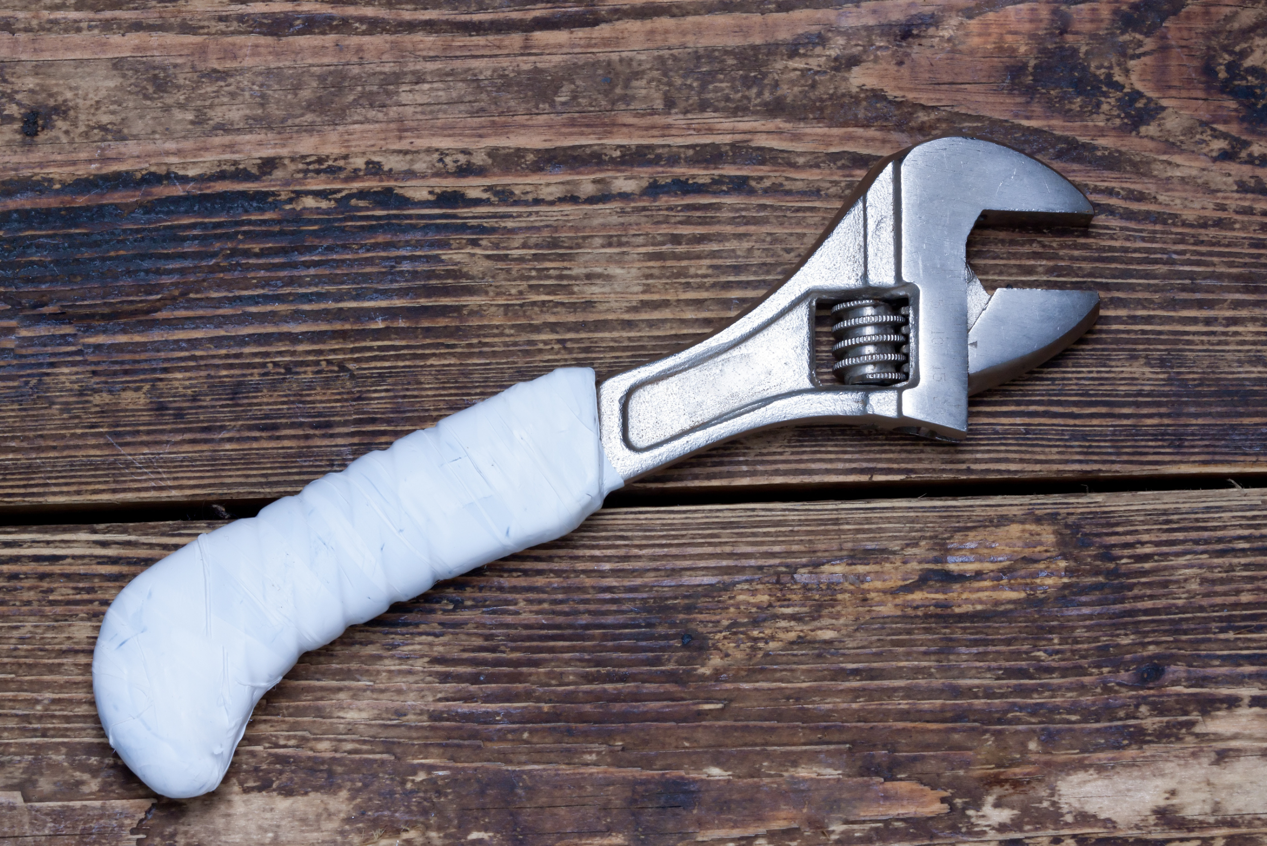 A metal adjustable wrench on a wooden table.