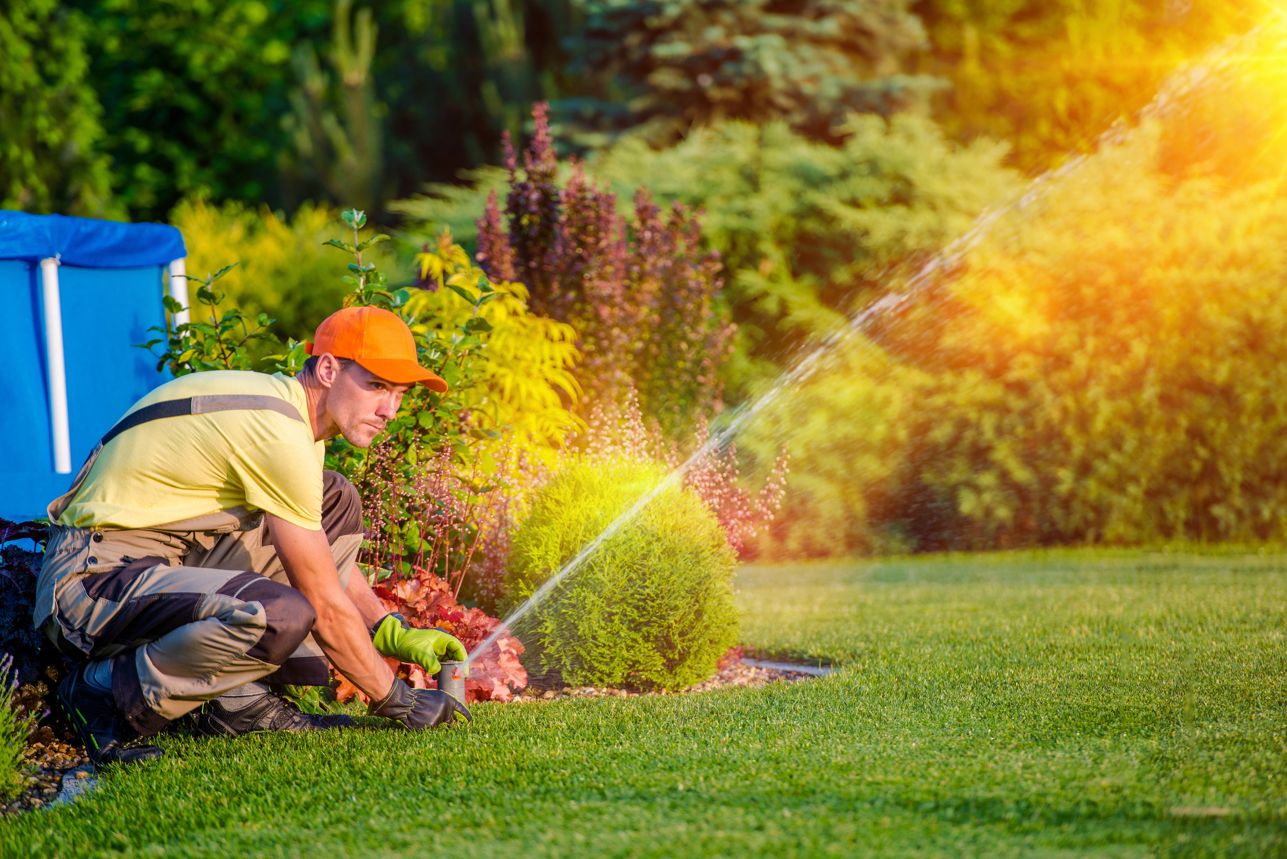 A person holding a sprinkler head as it sprays water.