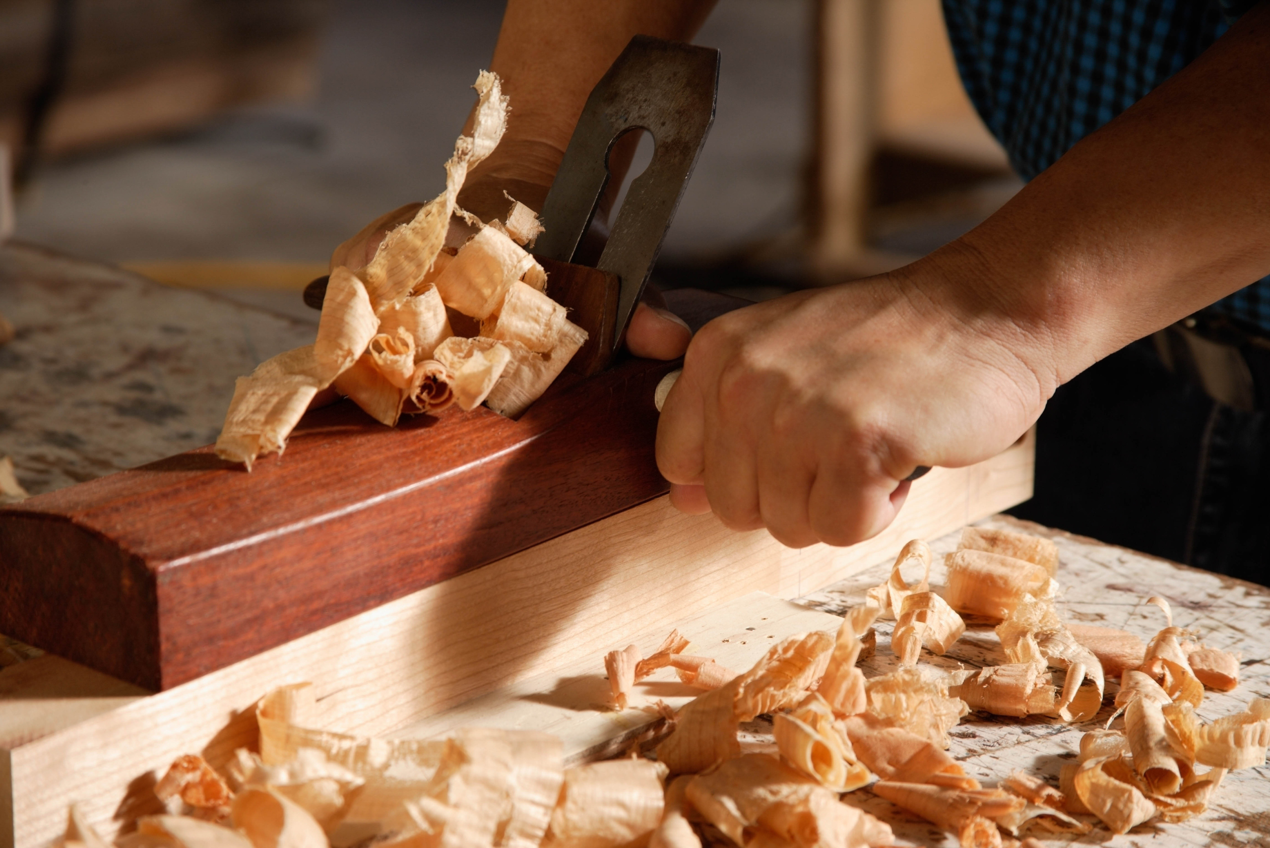 Hand planer in use with wood shavings.