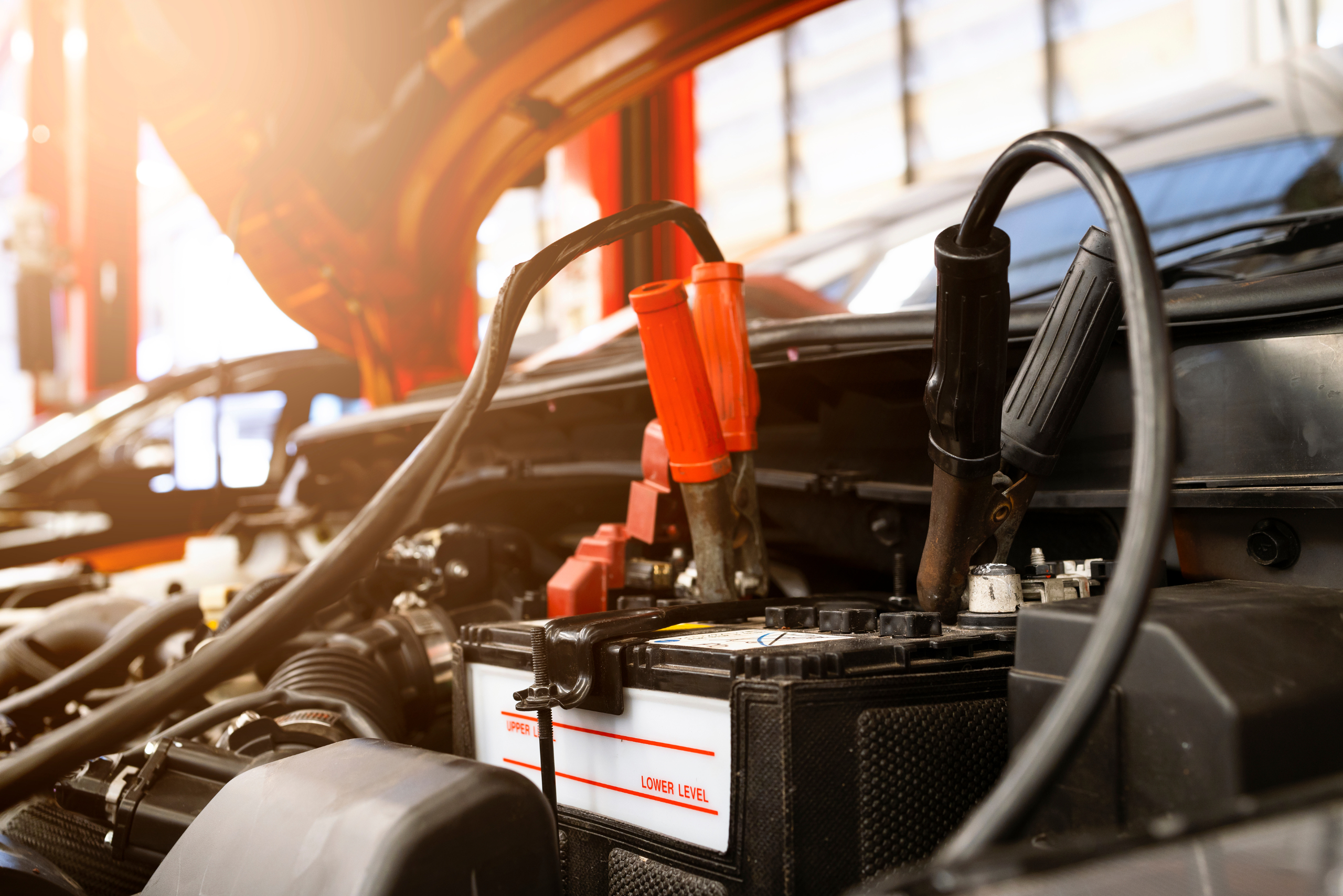 Jumper cables being attached to a car's battery under the hood.