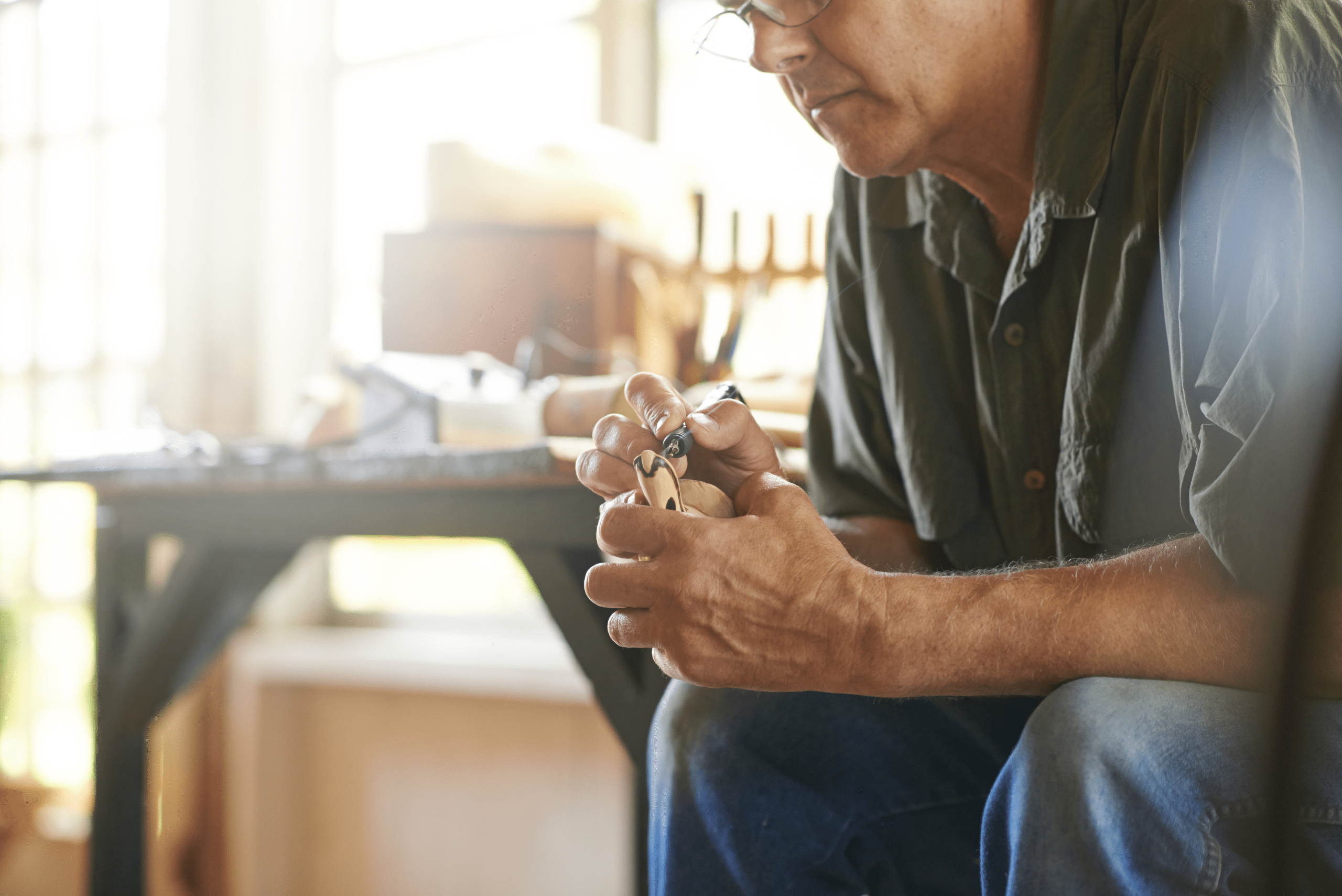 Person sitting and whittling wood.