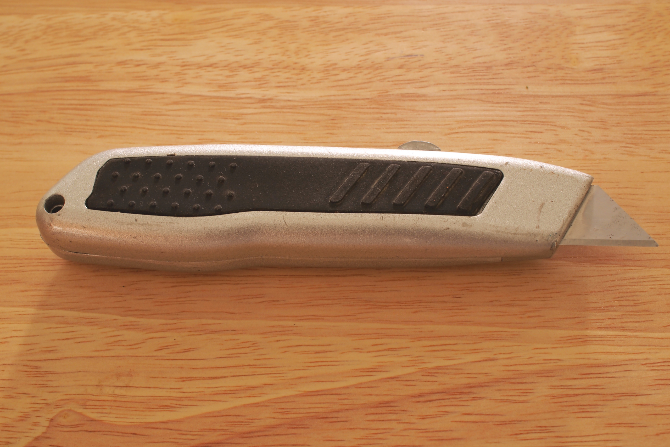 A utility knife on a wooden surface.