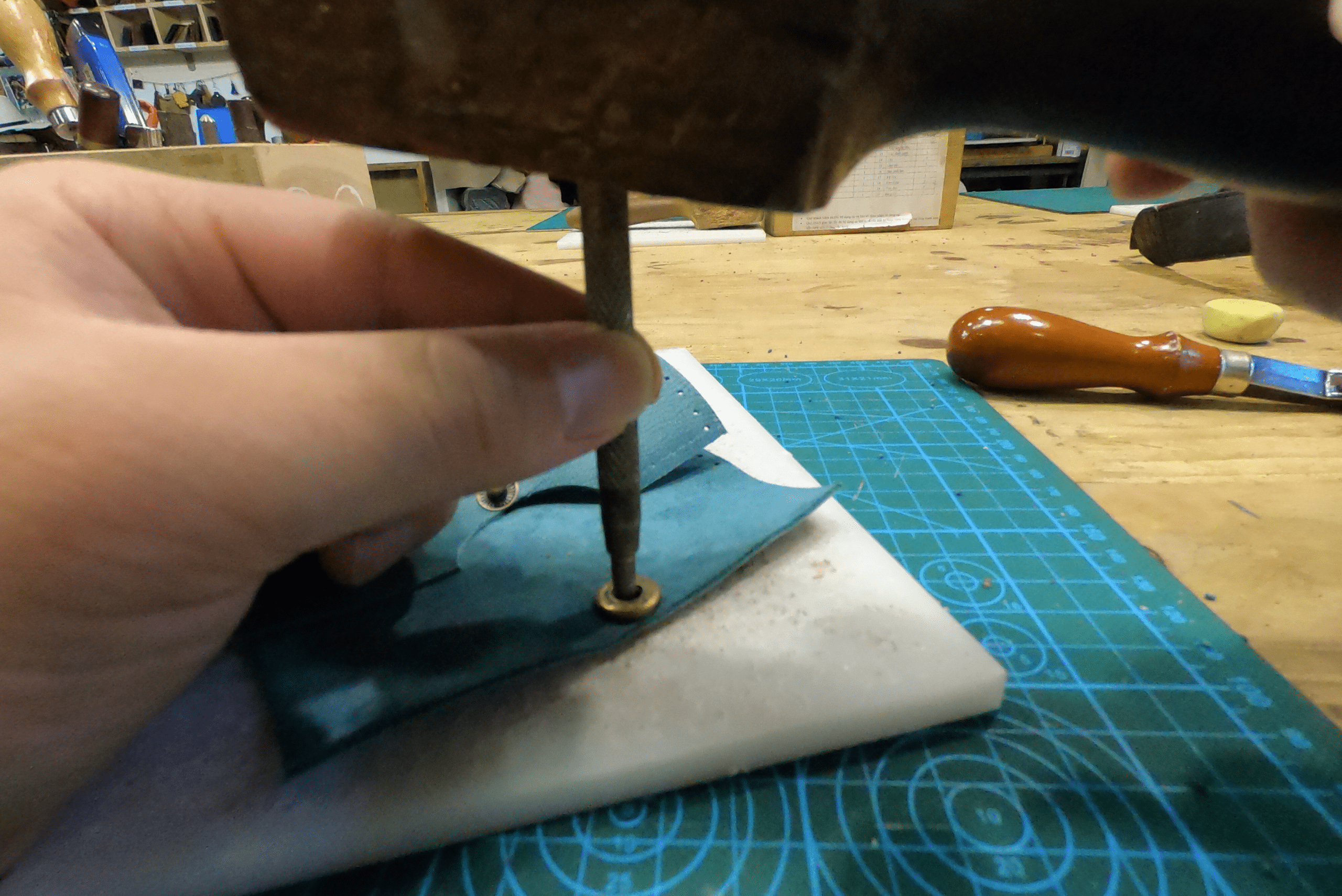 A punch is being used to finish up a leather wallet.