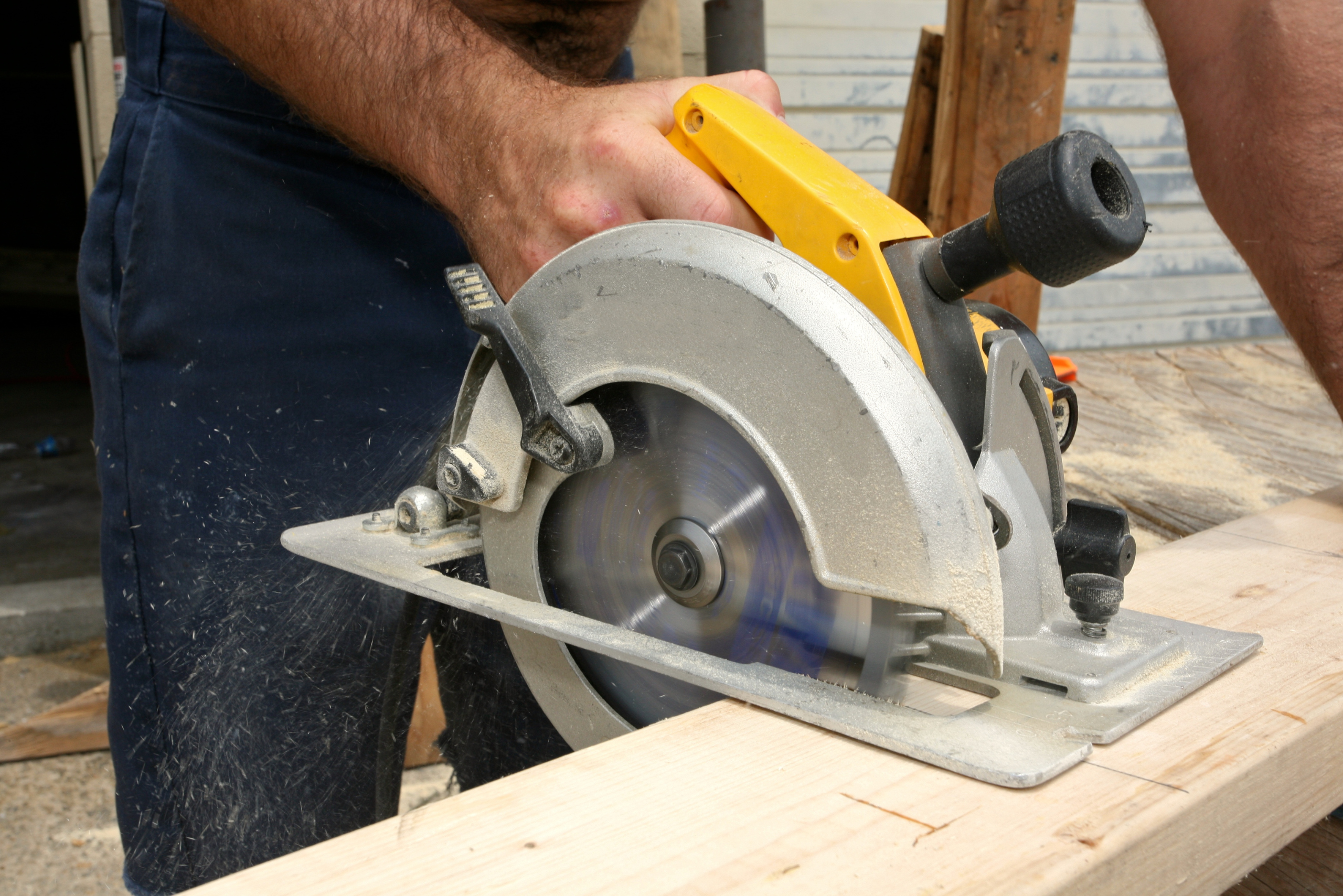 A person using a yellow circular saw for making a straight cut.