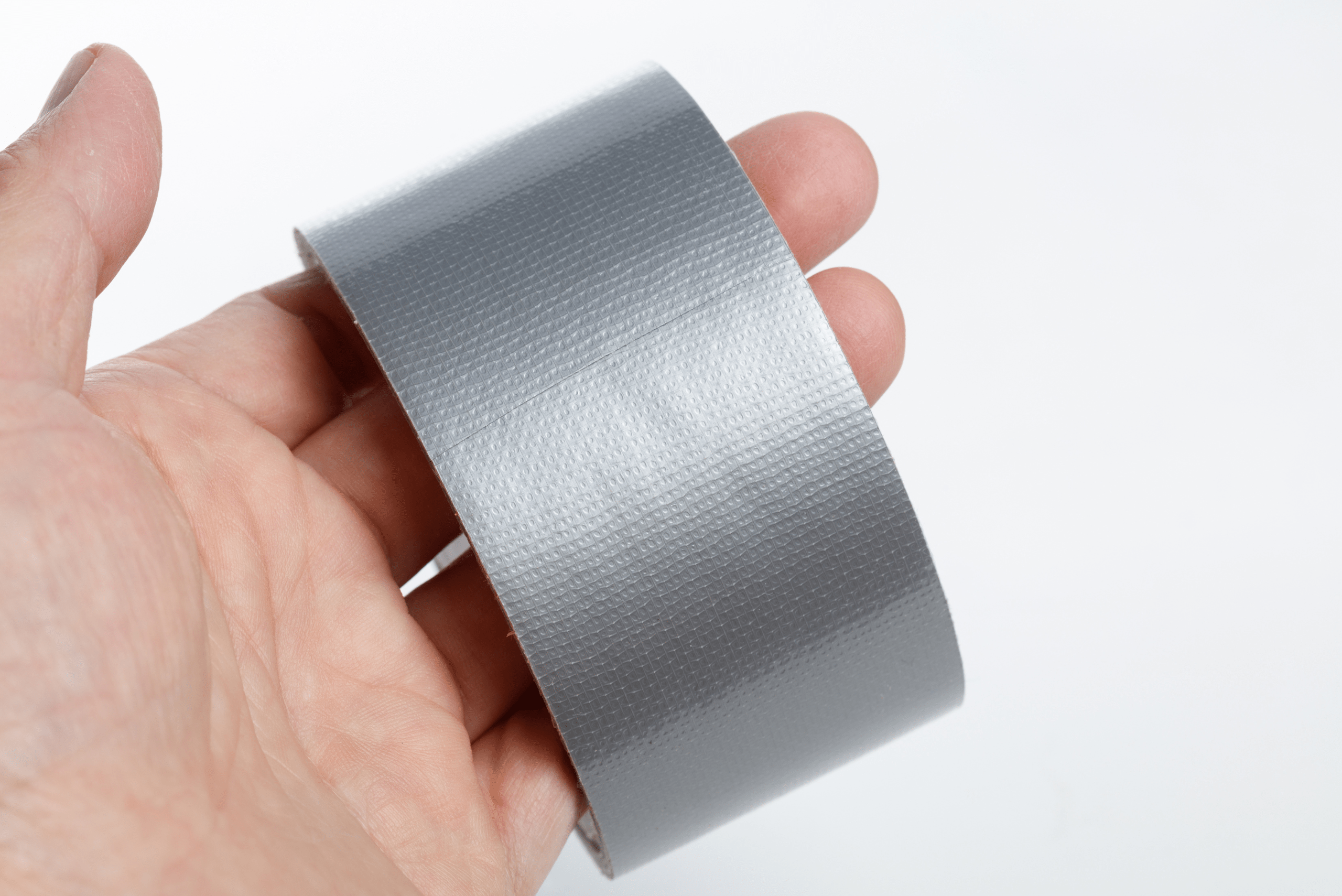 A person's hand holding a roll of duct tape.