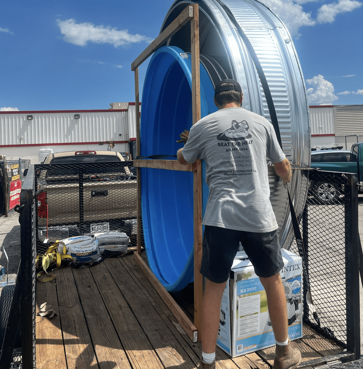 man loading a stock tank pool onto a trailer