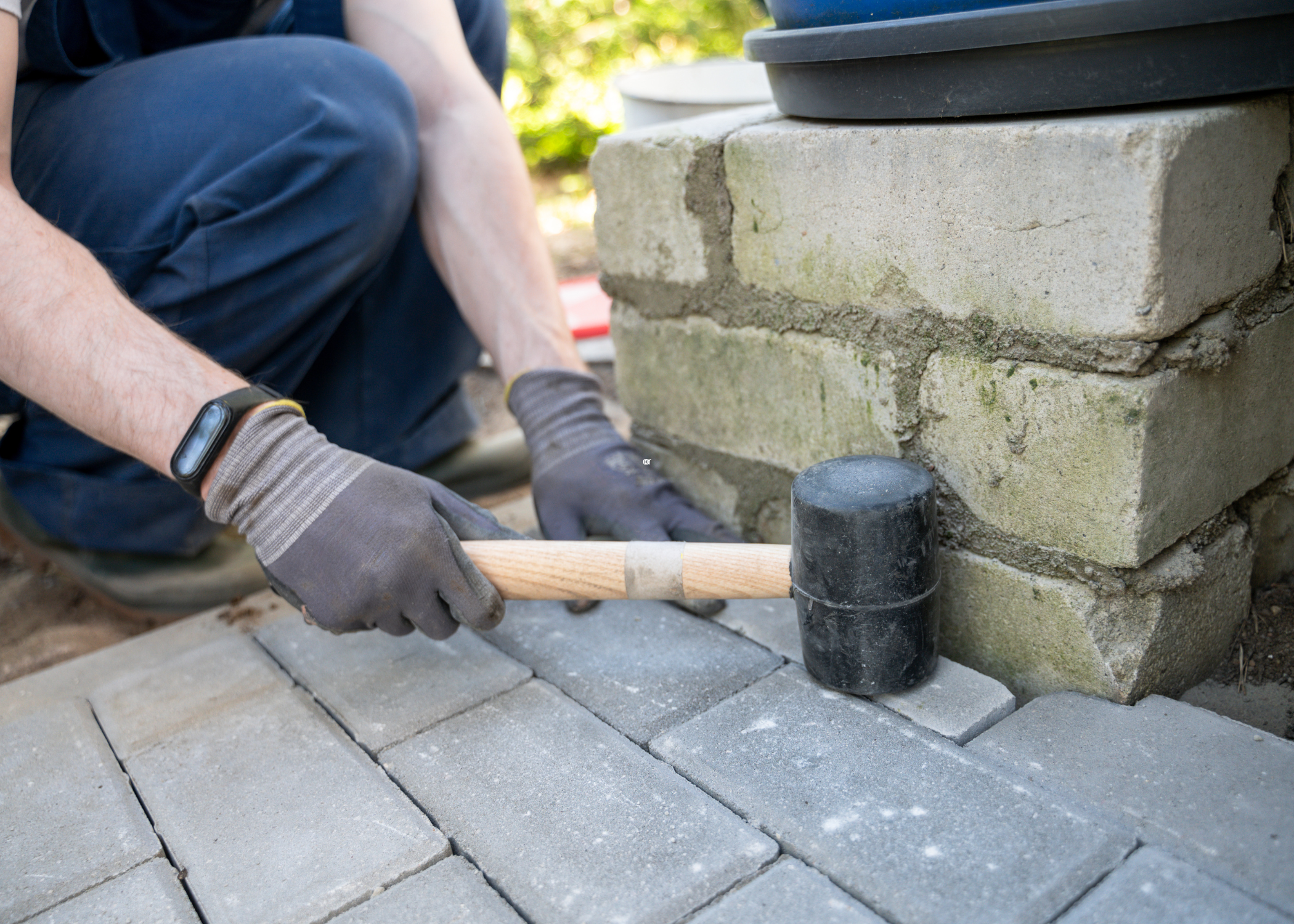 black rubber mallet being used to install concrete pavers