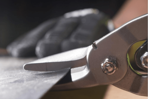 A pair of tin snips slicking through a metal sheet.