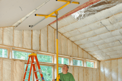 Person using a yellow drywall lift.