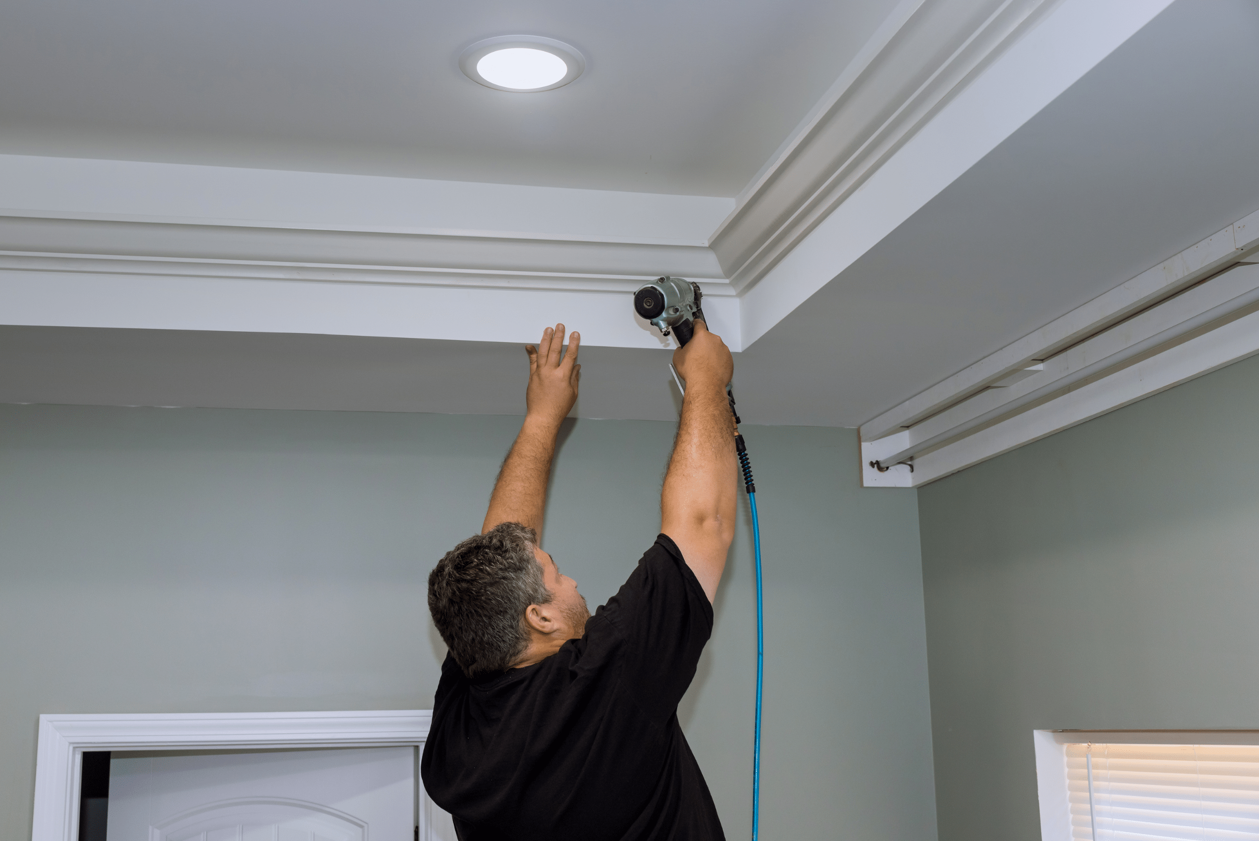 Worker installing crown molding.