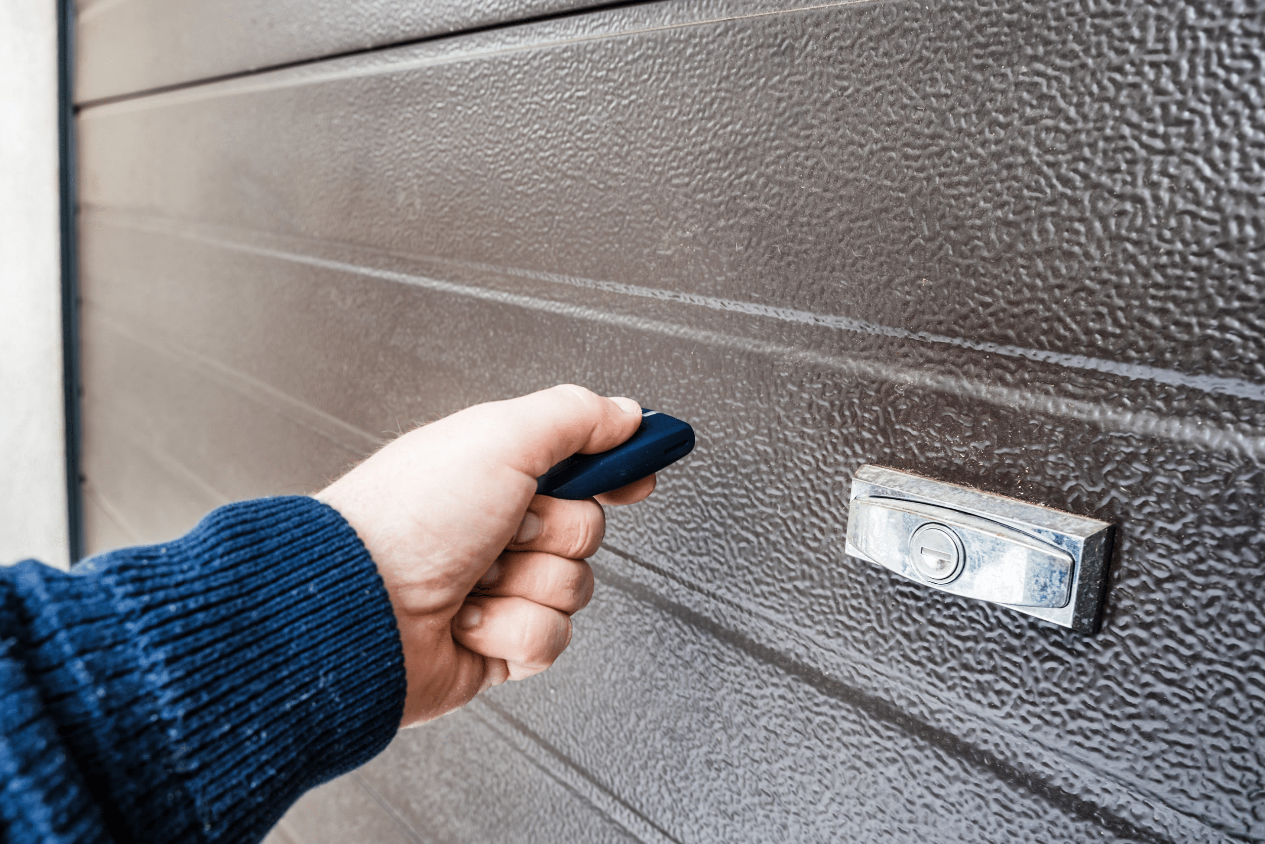 Hand using remote to open garage door.