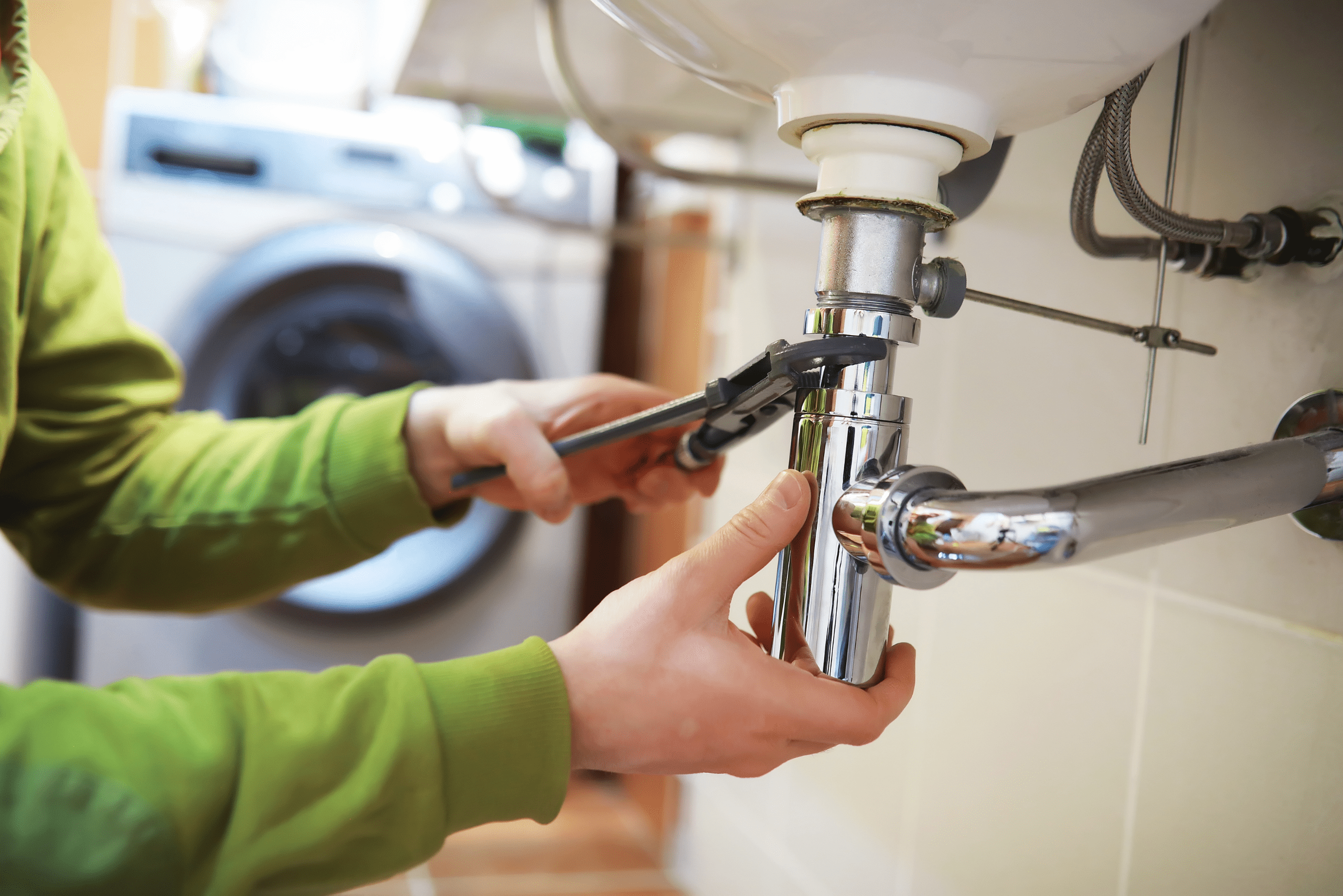 Person using wrench to tighten a plumbing connection of a sink.