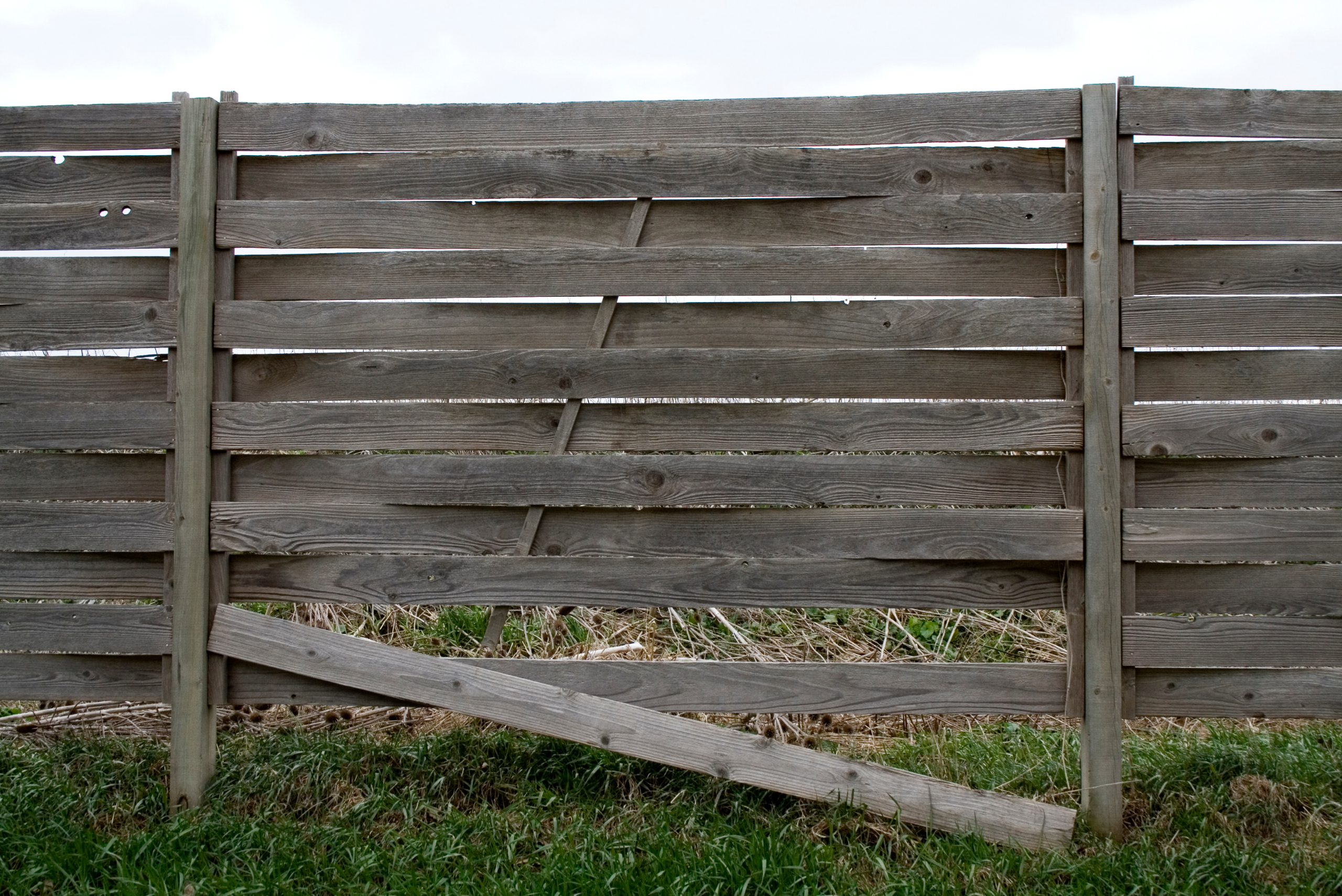 Wooden fence with board hanging down.