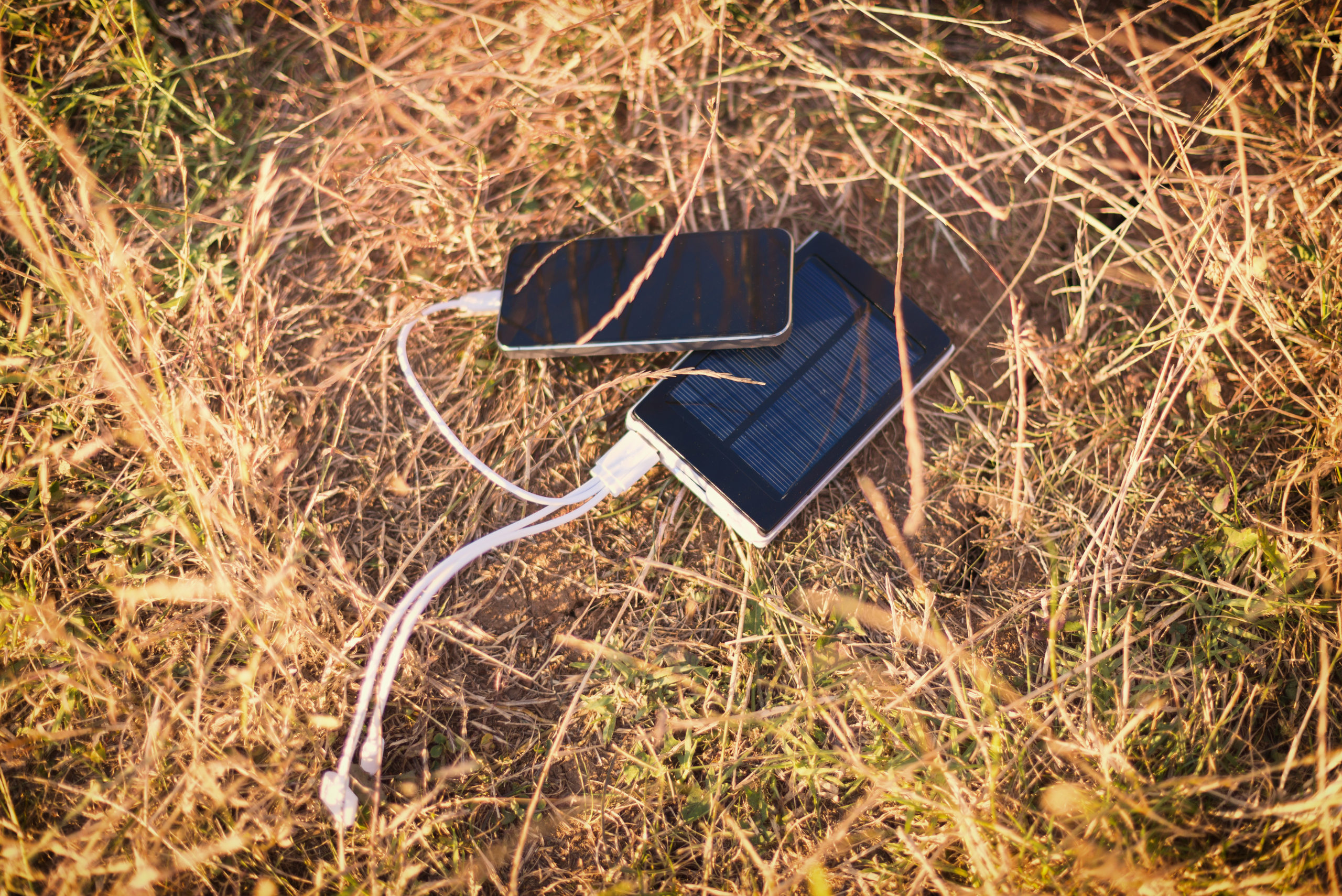 Phone and solar panel on top of hay.