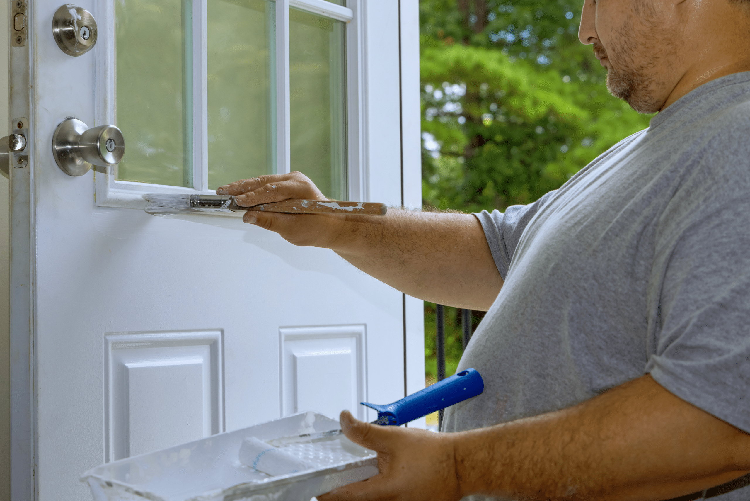 Person repainting a white front door.