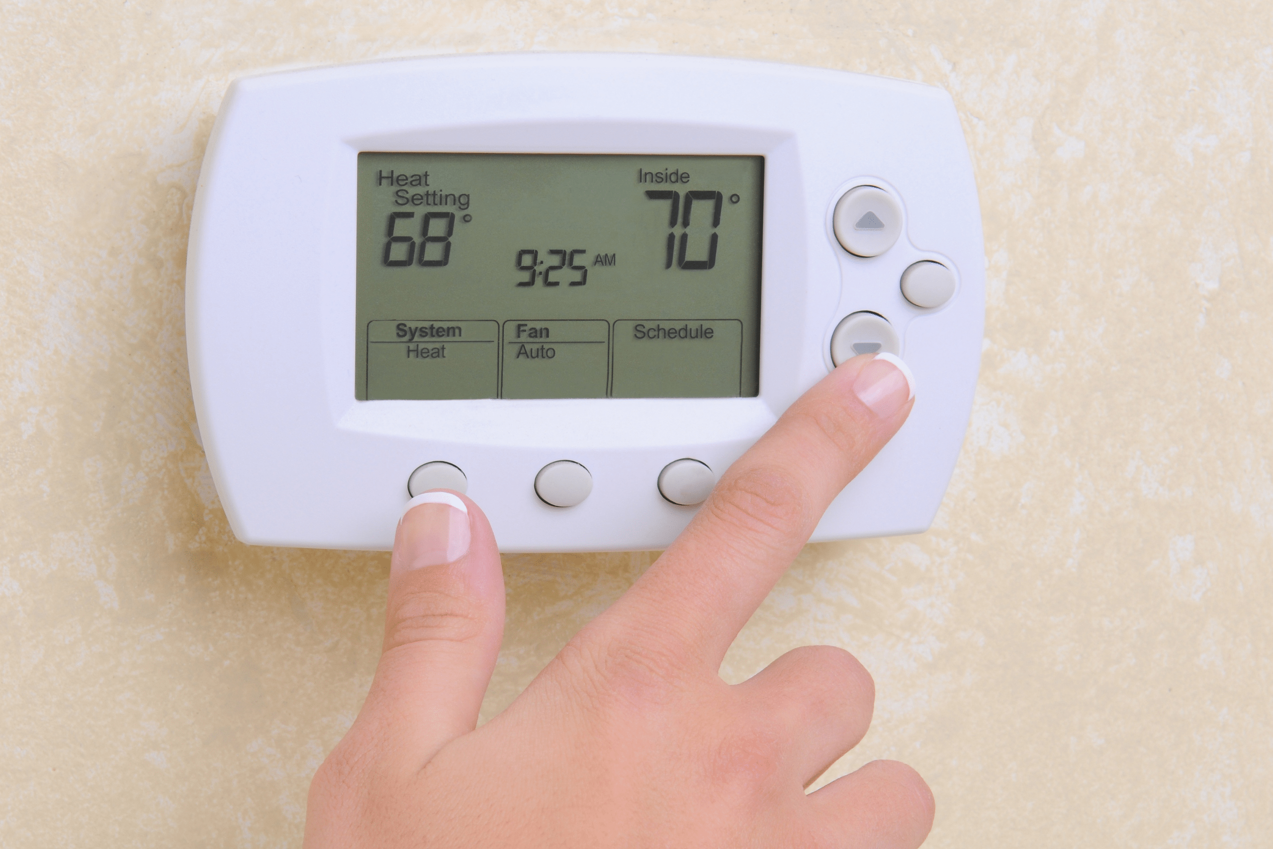 A person using a home thermostat.