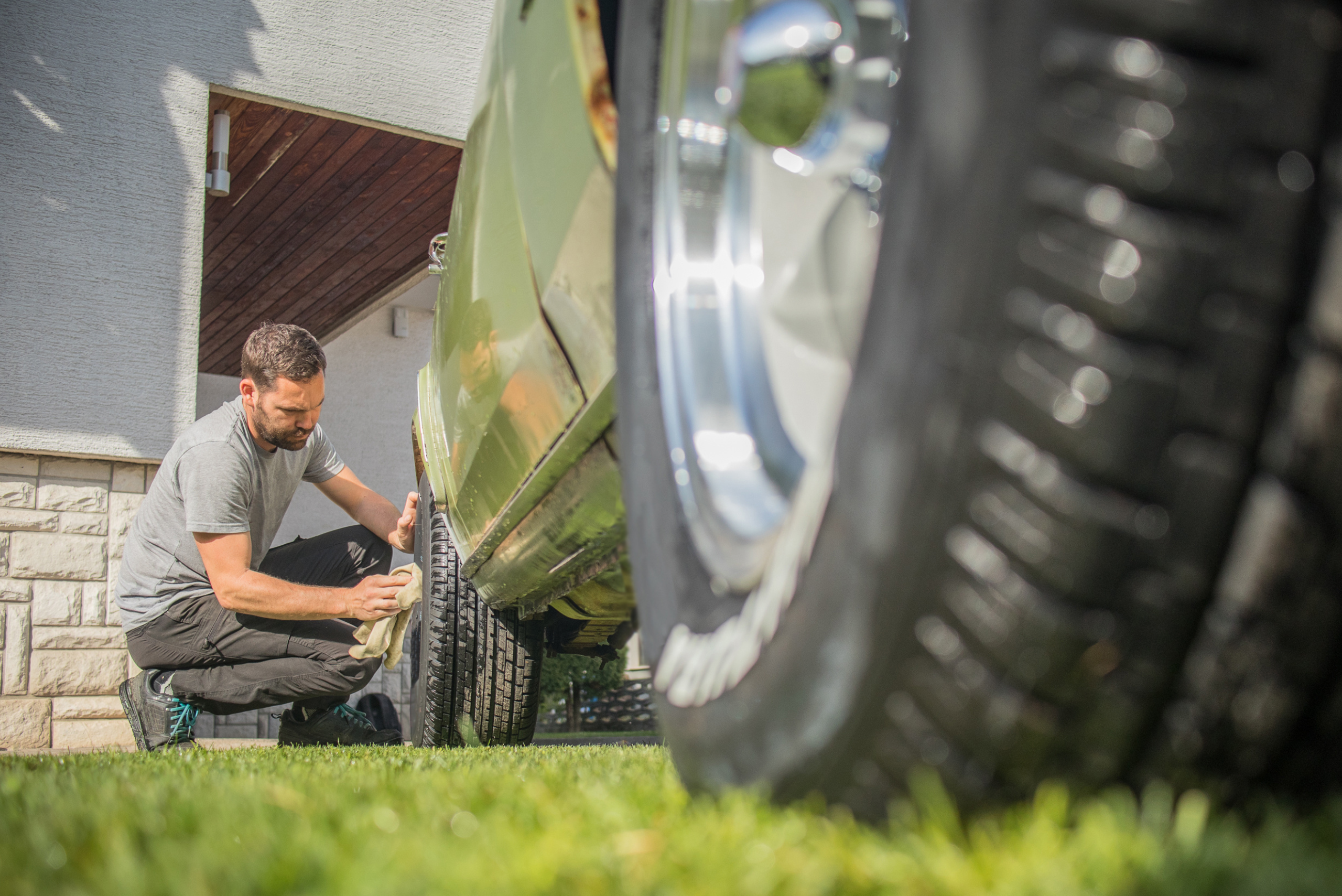 Man using a cloth to clean car wheel.