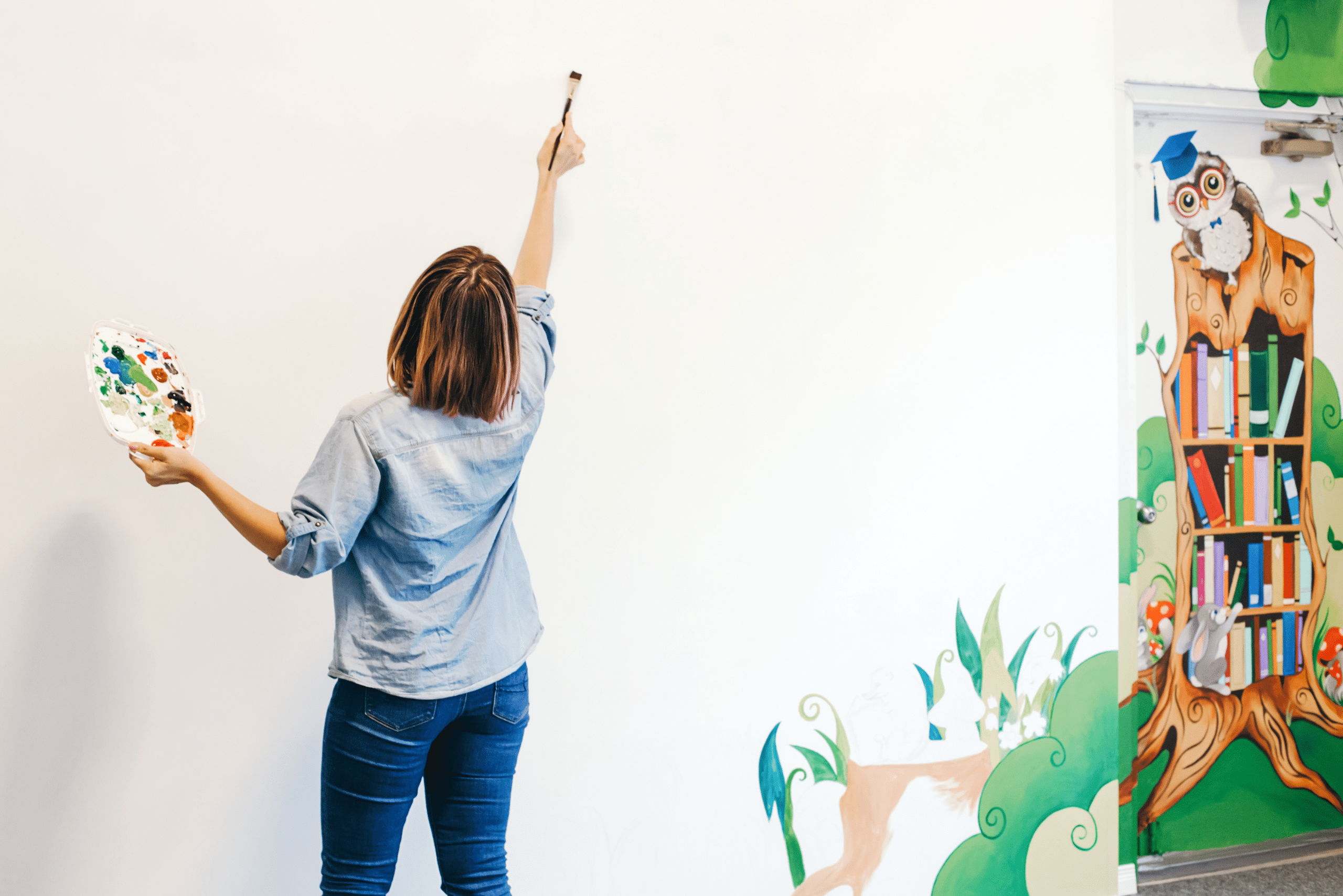 Woman drawing mural on wall.