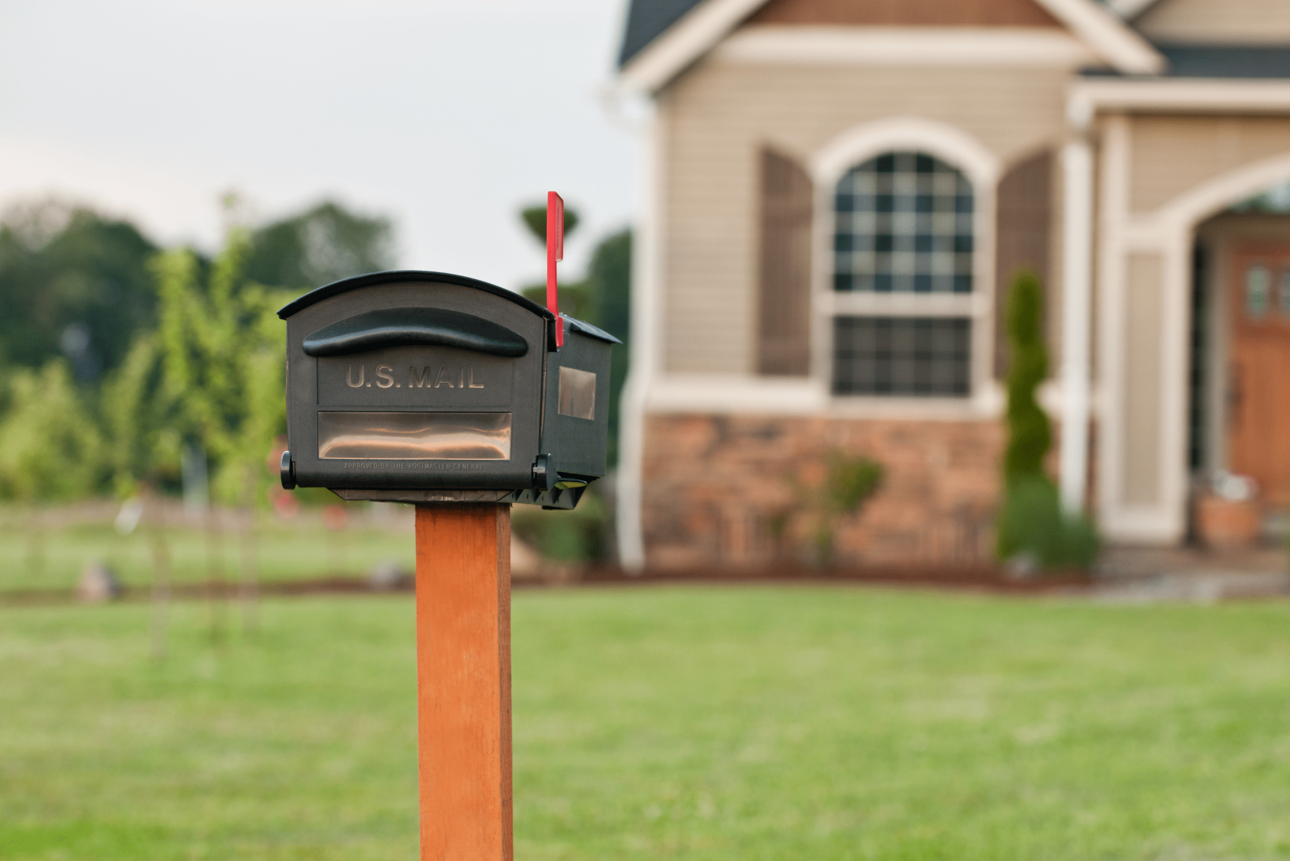 House black mailbox with wooden post.