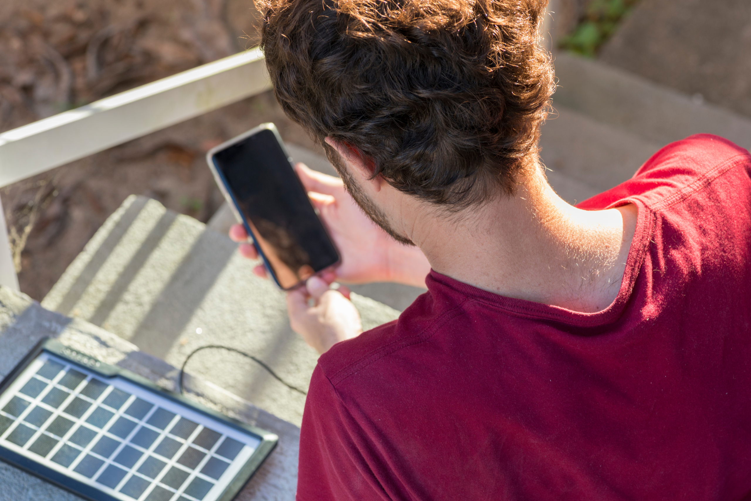 Man using solar panel to charge phone.